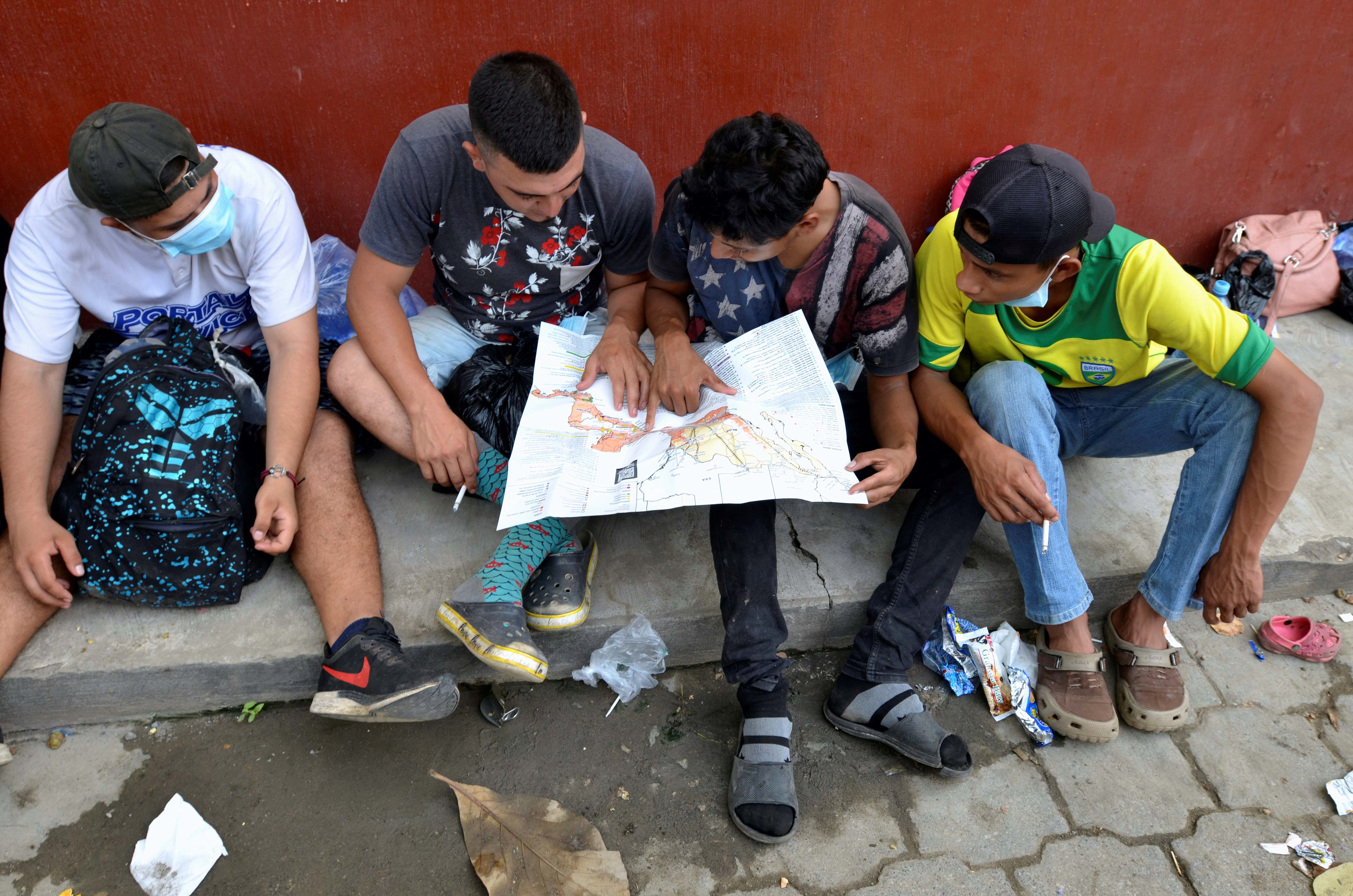 A group of Honduran migrants who are trying to reach the United States look at a Central America and Mexico map outside a migrant shelter as they wait to move towards the Guatemala and Mexico border, in Tecun Uman, Guatemala