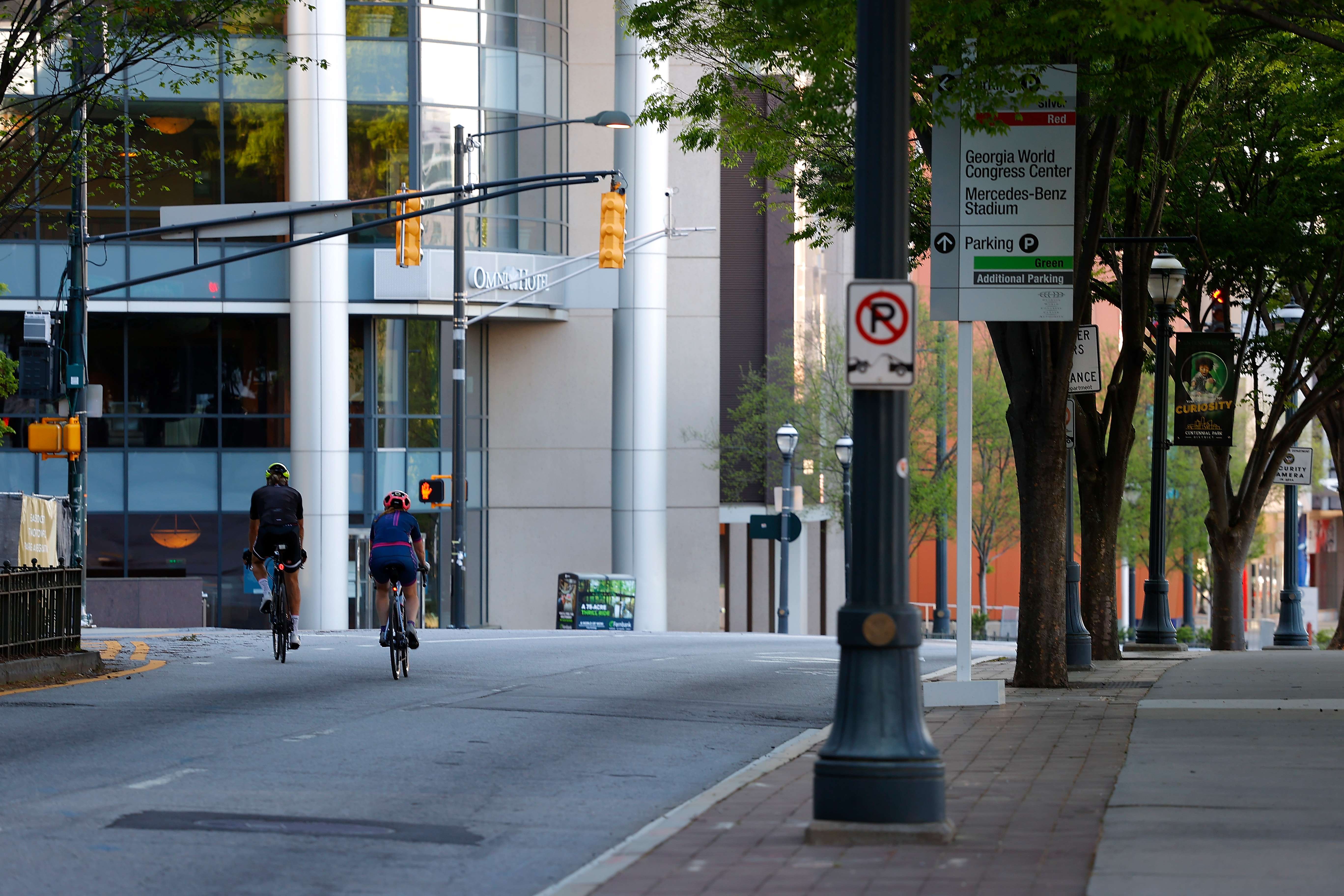 Two cyclists are seen riding down an empty Marietta Street NW in between the CNN Center and Centennial Olympic Park on April 4, 2020 in Atlanta, Georgia