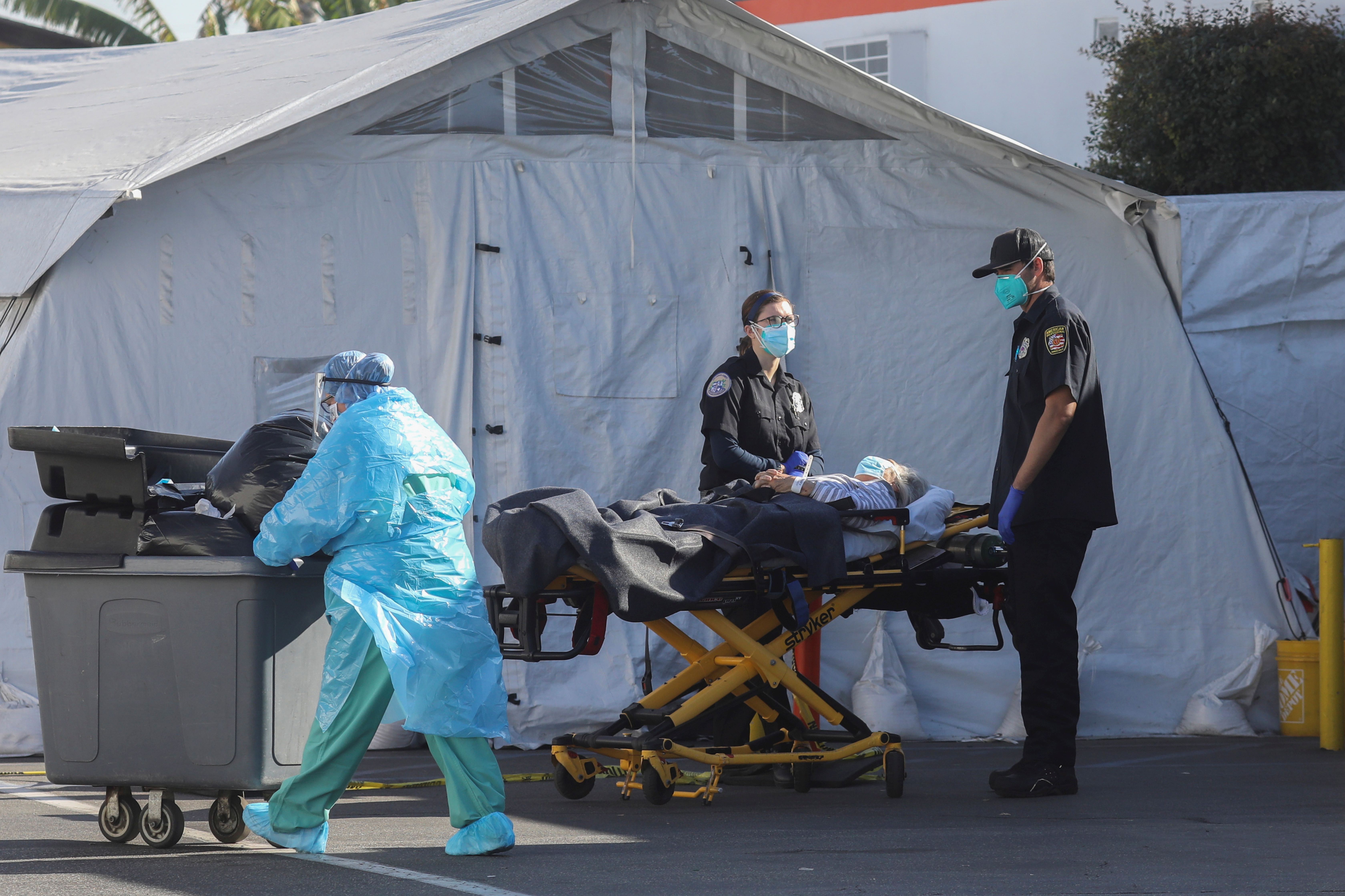 An ambulance crew waits with a patient outside the Coast Plaza Hospital emergency room during a surge of coronavirus cases in Los Angeles in the United States