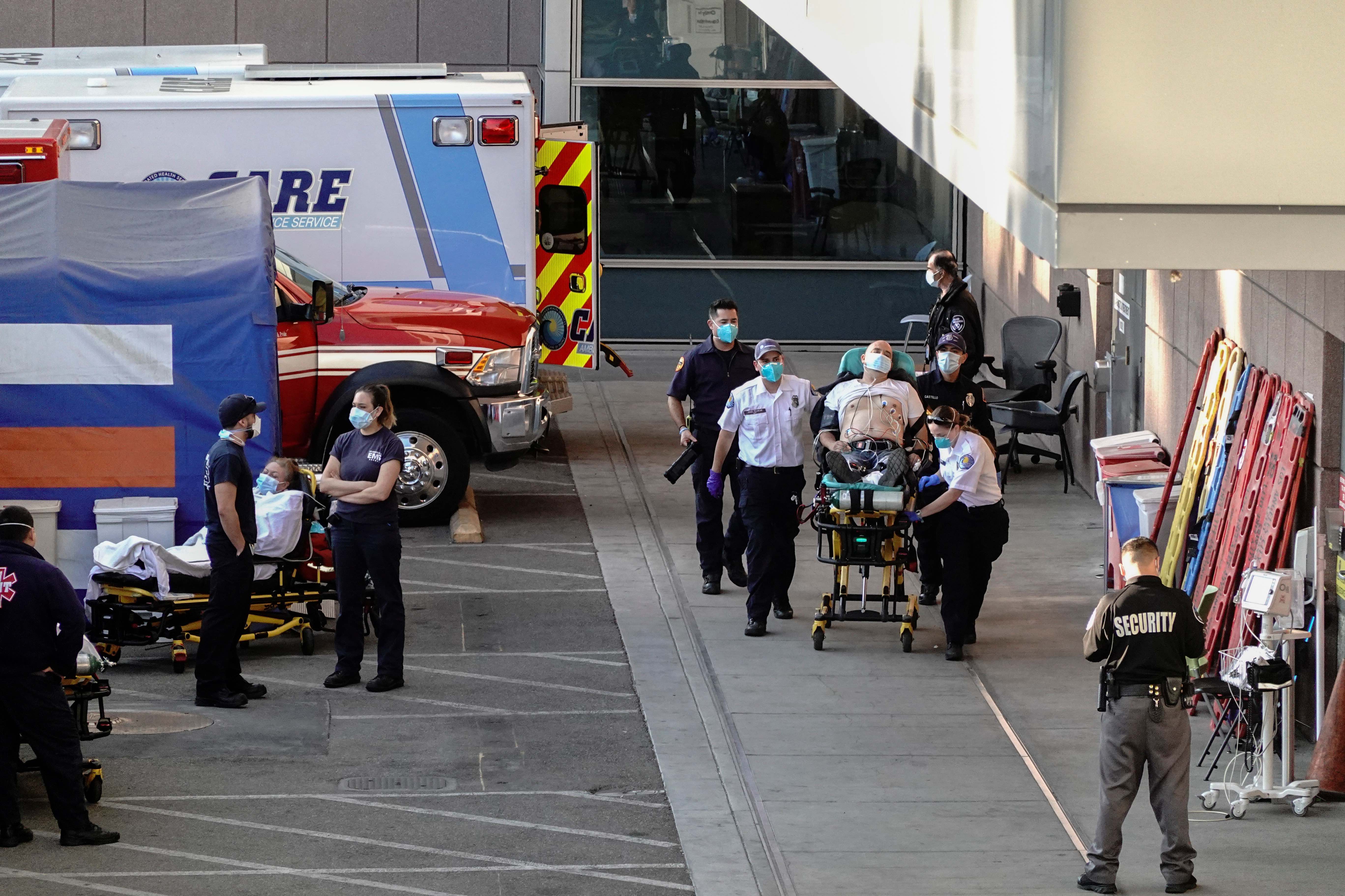 Paramedics escort a patient from the ambulance entrance to the emergency room at LAC + USC Medical Center in Los Angeles, California