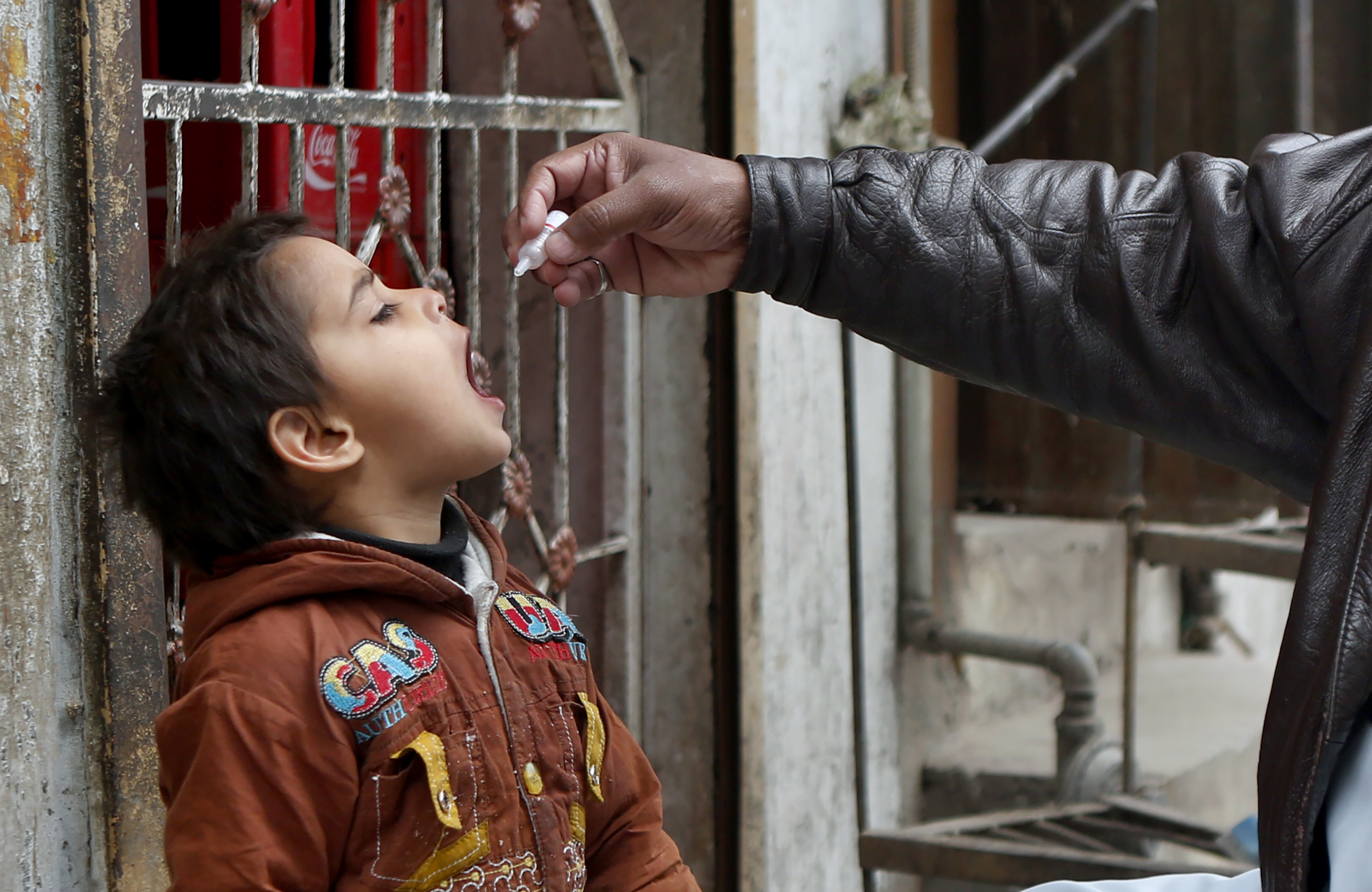 A healthcare worker administers a polio vaccine to a child in Lahore