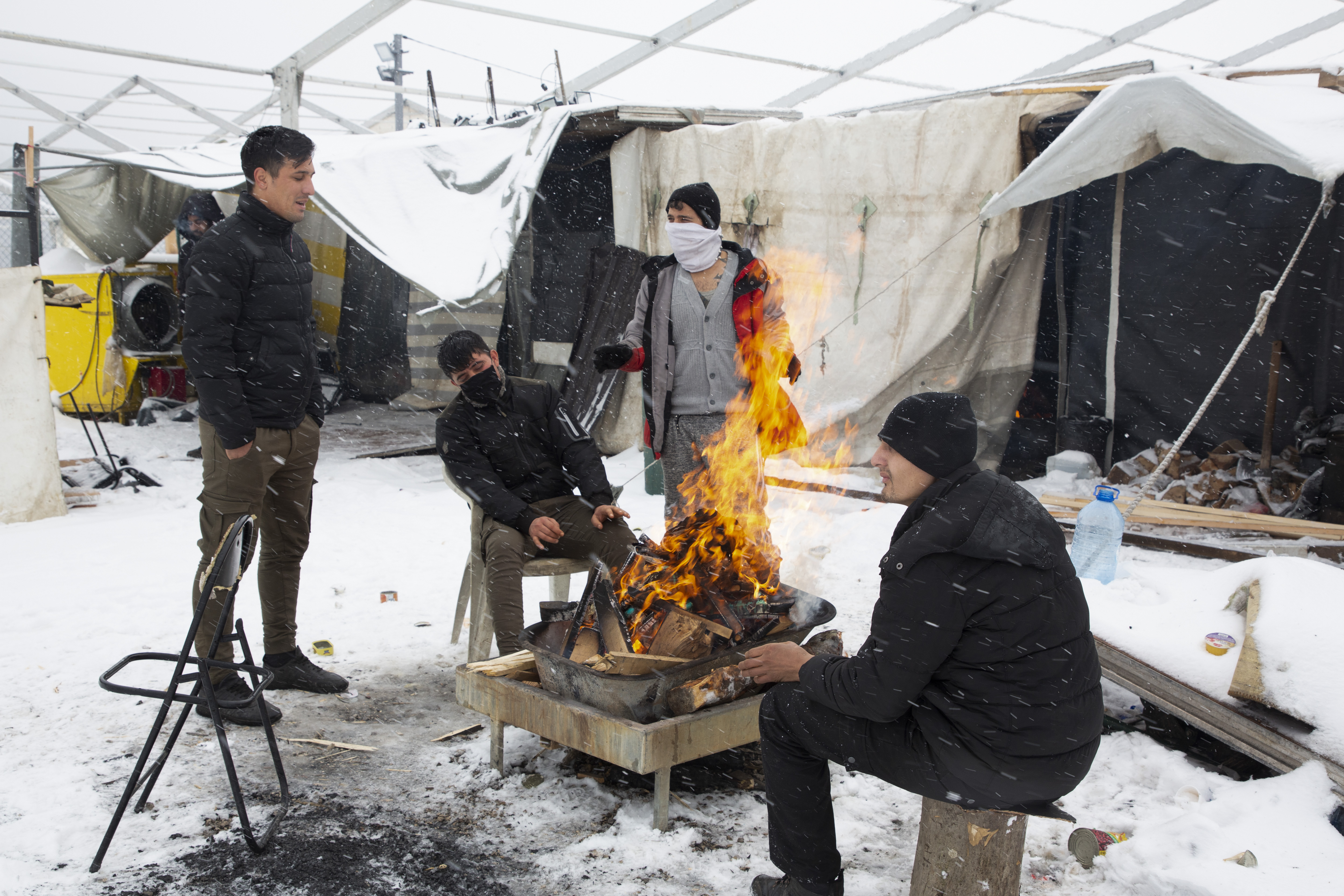 Refugees light fires in an attempt to warm up in Lipa, Bosnia