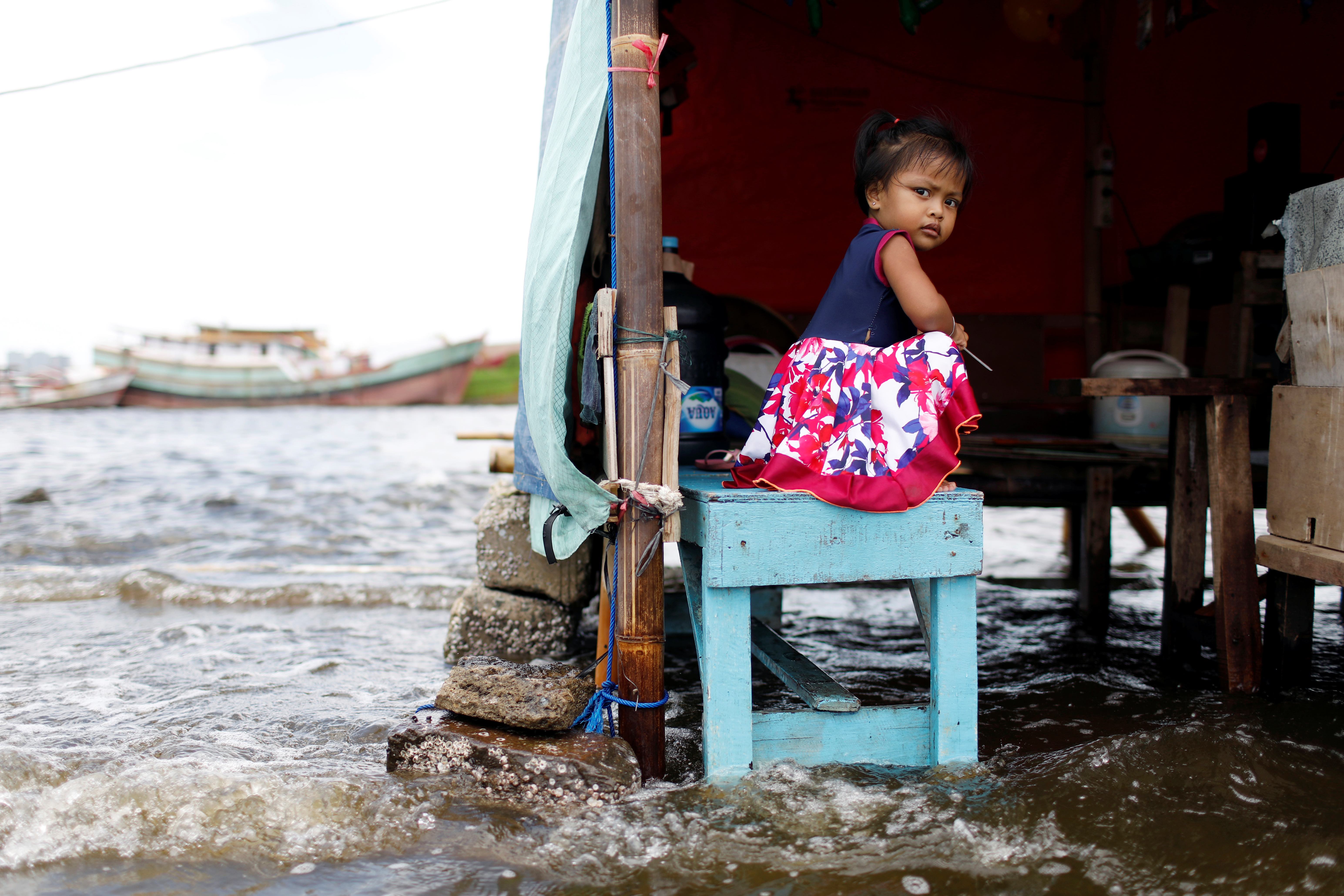Shaqueena Dwi Arsyilla, age two, sits on a bench at Kali Adem port, which is impacted by high tides due to the rising sea level and land subsidence, north of Jakarta, Indonesia