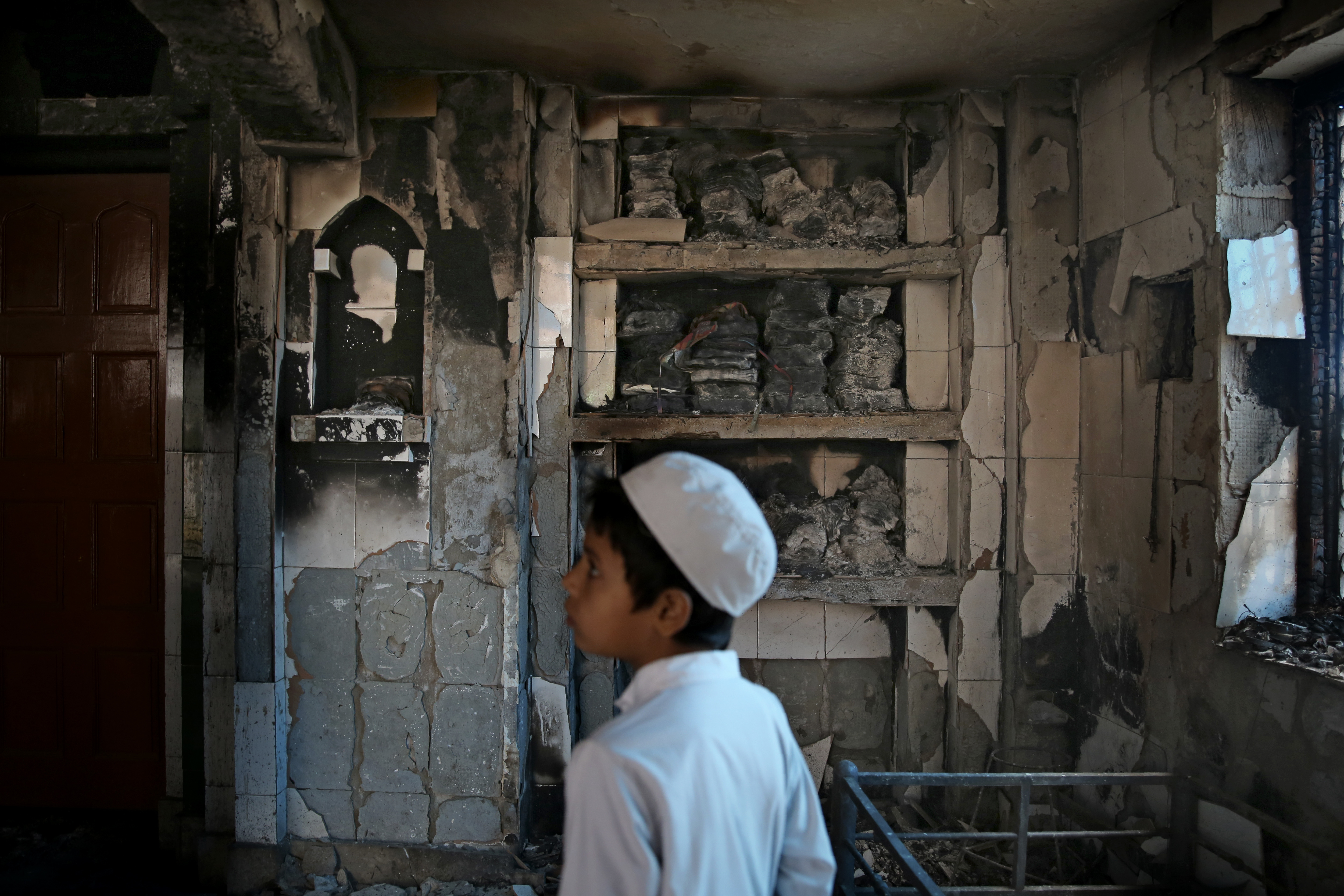 In this February 27, 2020 photo, a boy stands inside a mosque torched during Delhi riots