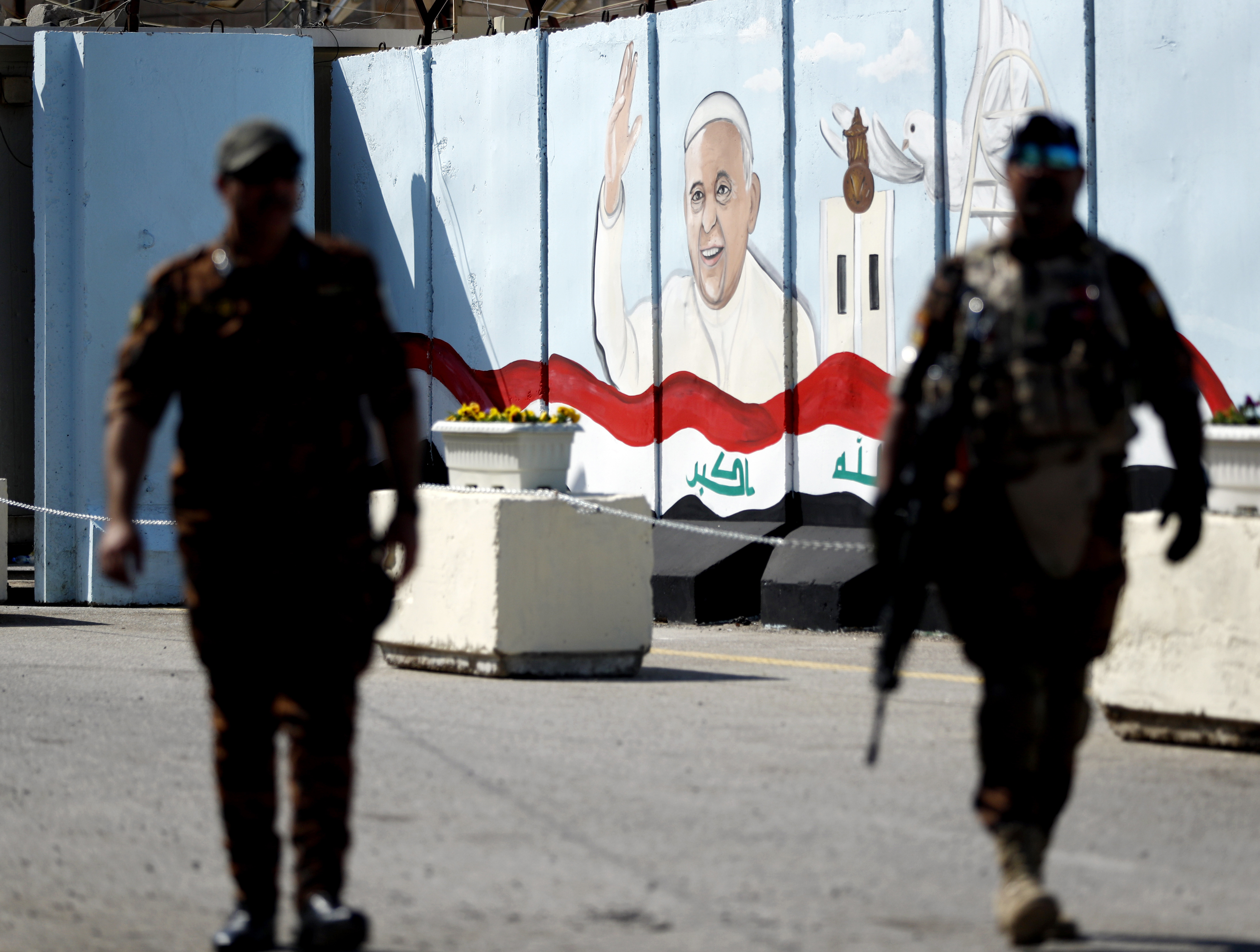 Federal policemen patrol by a concrete wall placed by Iraqi security forces to surround the Our Lady of Salvation Church during preparations for the pope’s visit in Baghdad