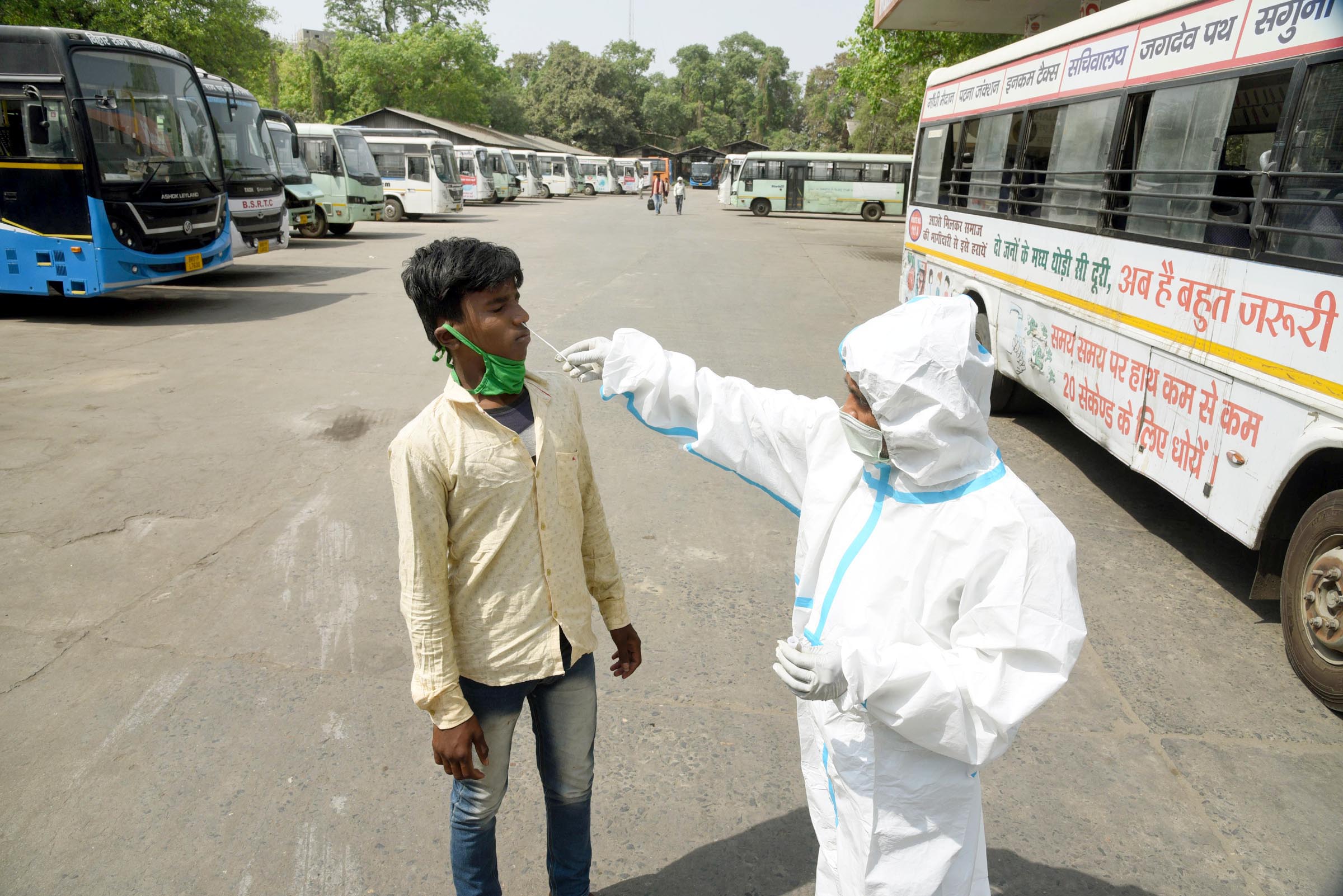 A health worker collects swab sample from a passenger at a government bus stand near Gandhi Maidan, amid the coronavirus pandemic, on April 12, 2021 in Patna, India