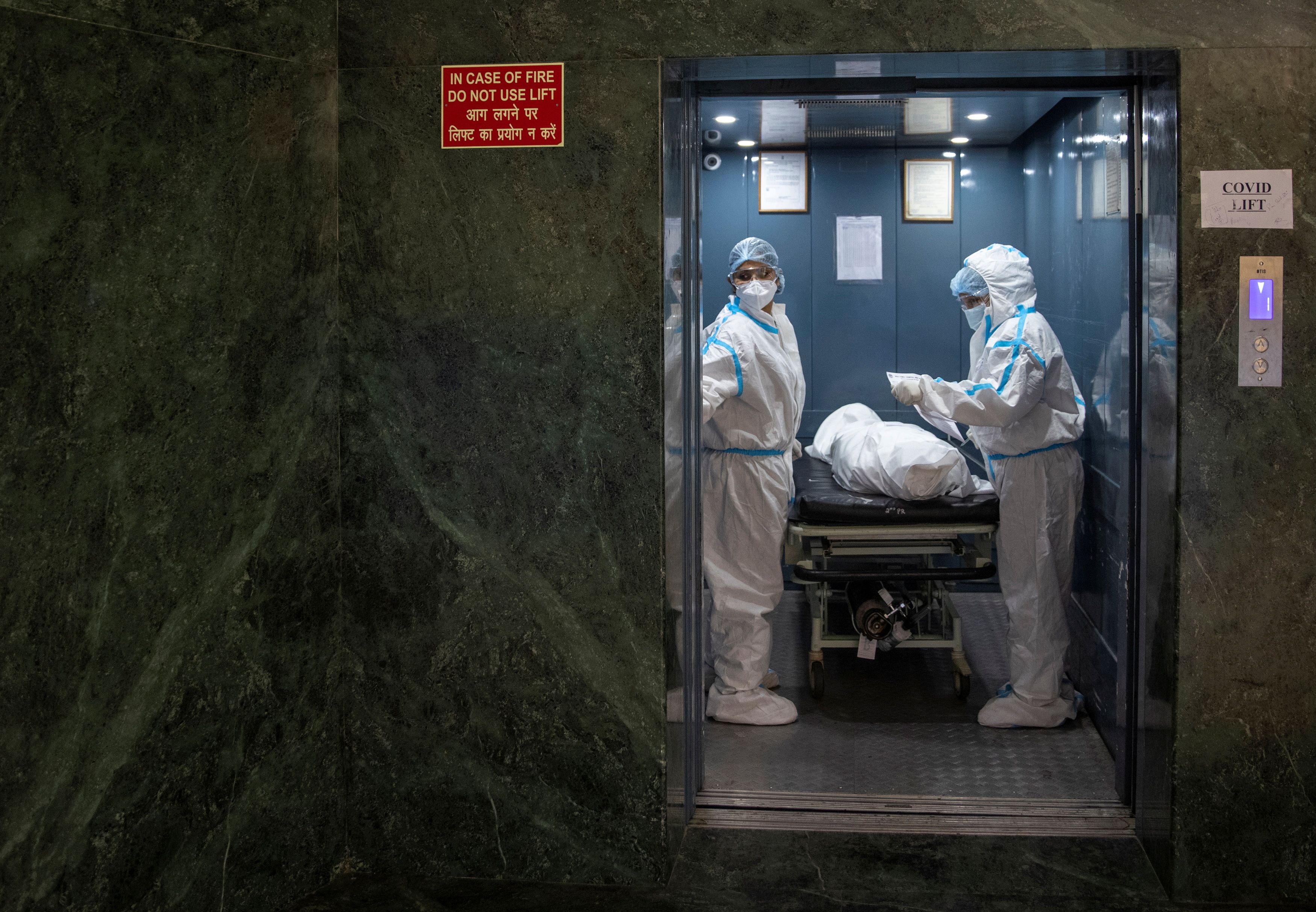 Hospital workers carry the body of a person who died from complications related to the coronavirus
