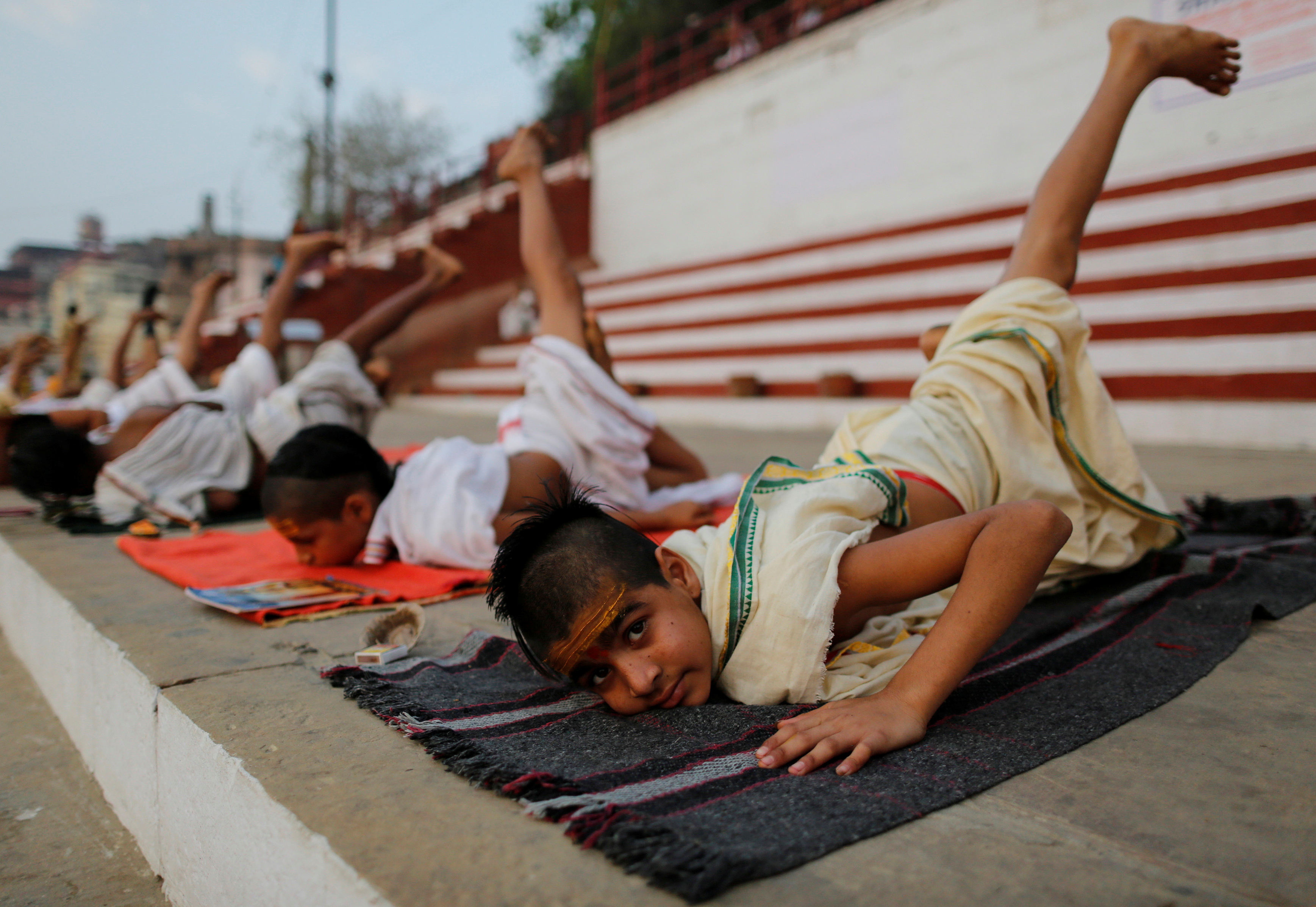 Students from a Hindu religious school practising yoga on the banks of the River Ganges in Varanasi, India