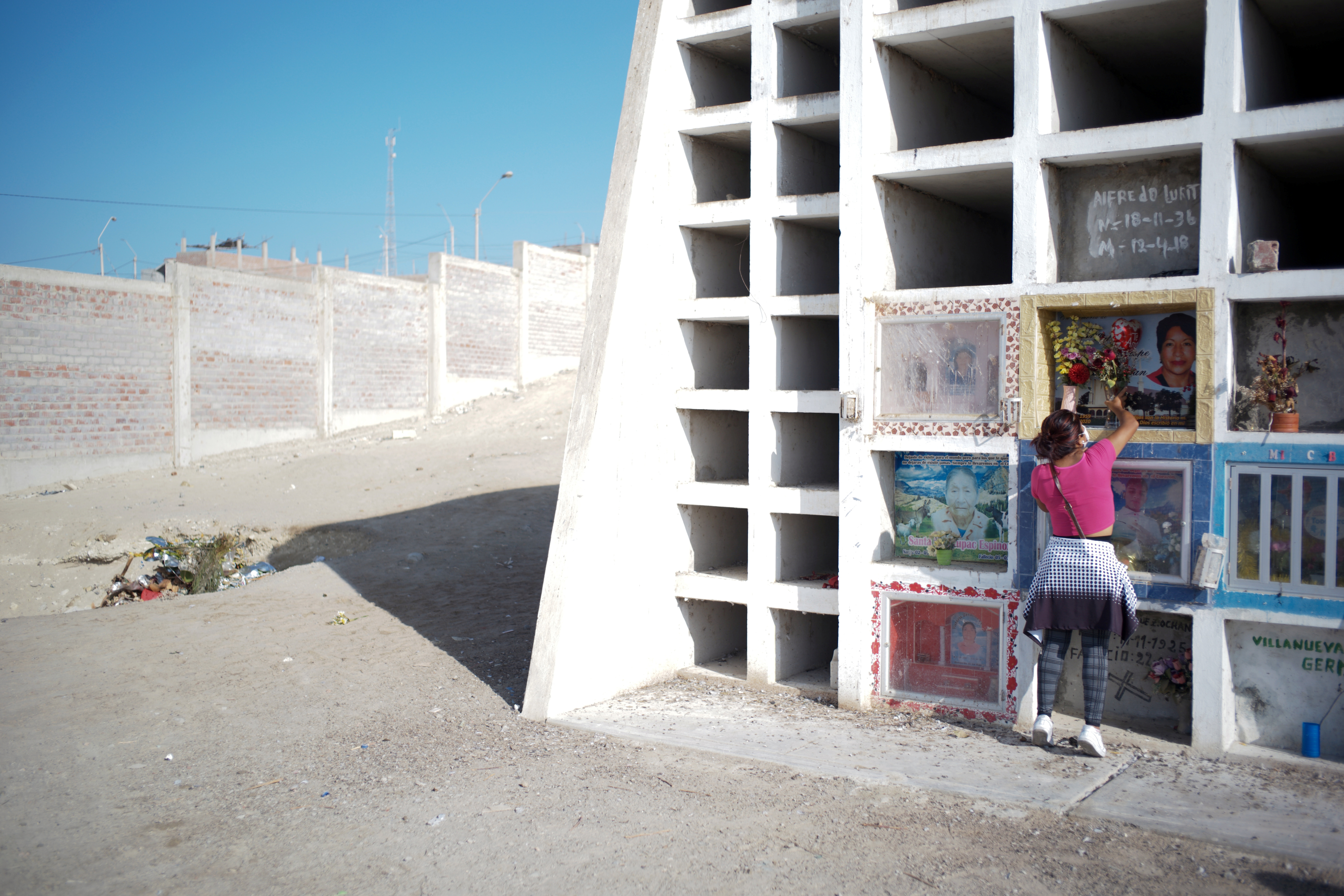 A woman visits a grave at a cemetery in Peru