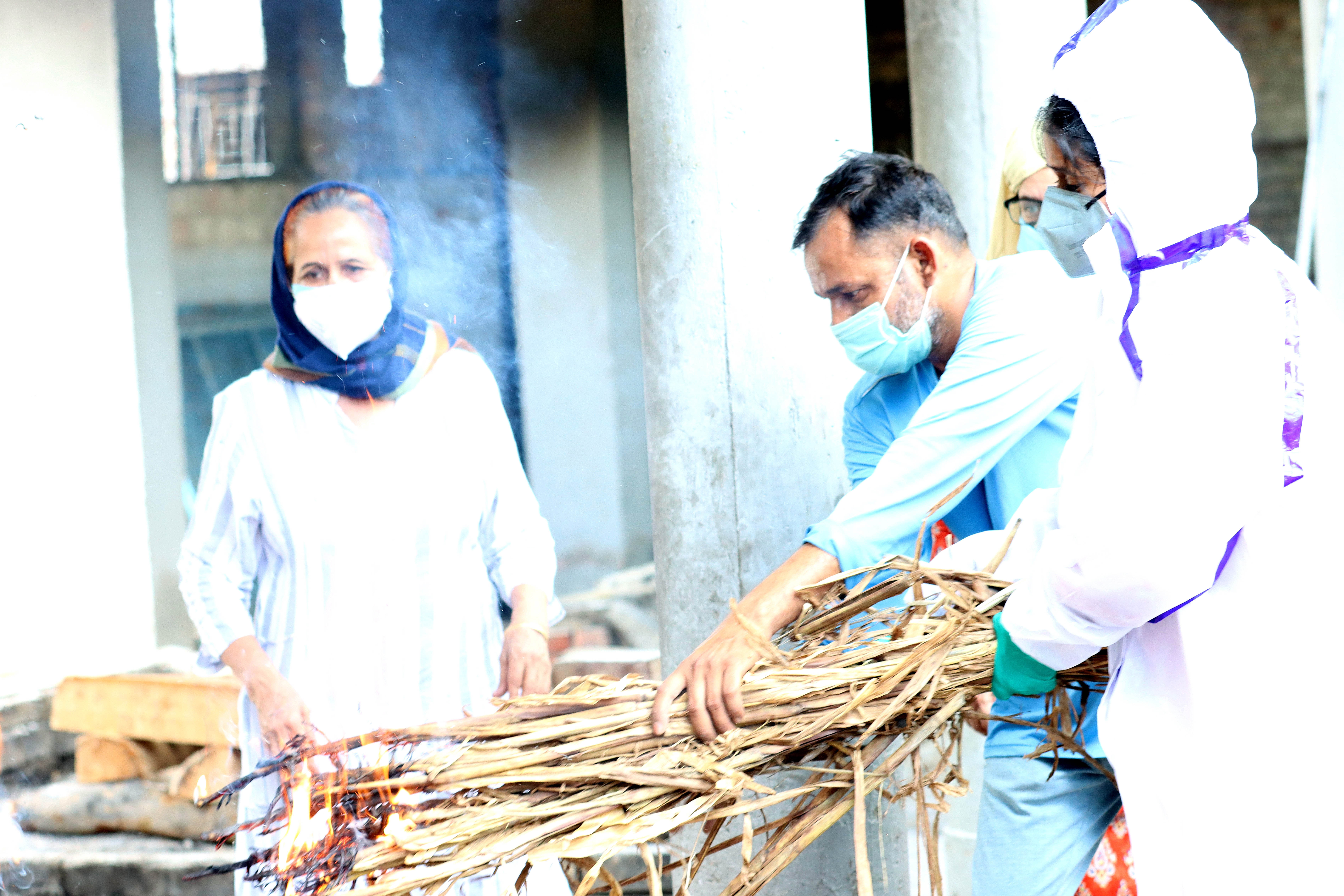 Natasha Narwal, in PPE coveralls, performing the last rites of her father