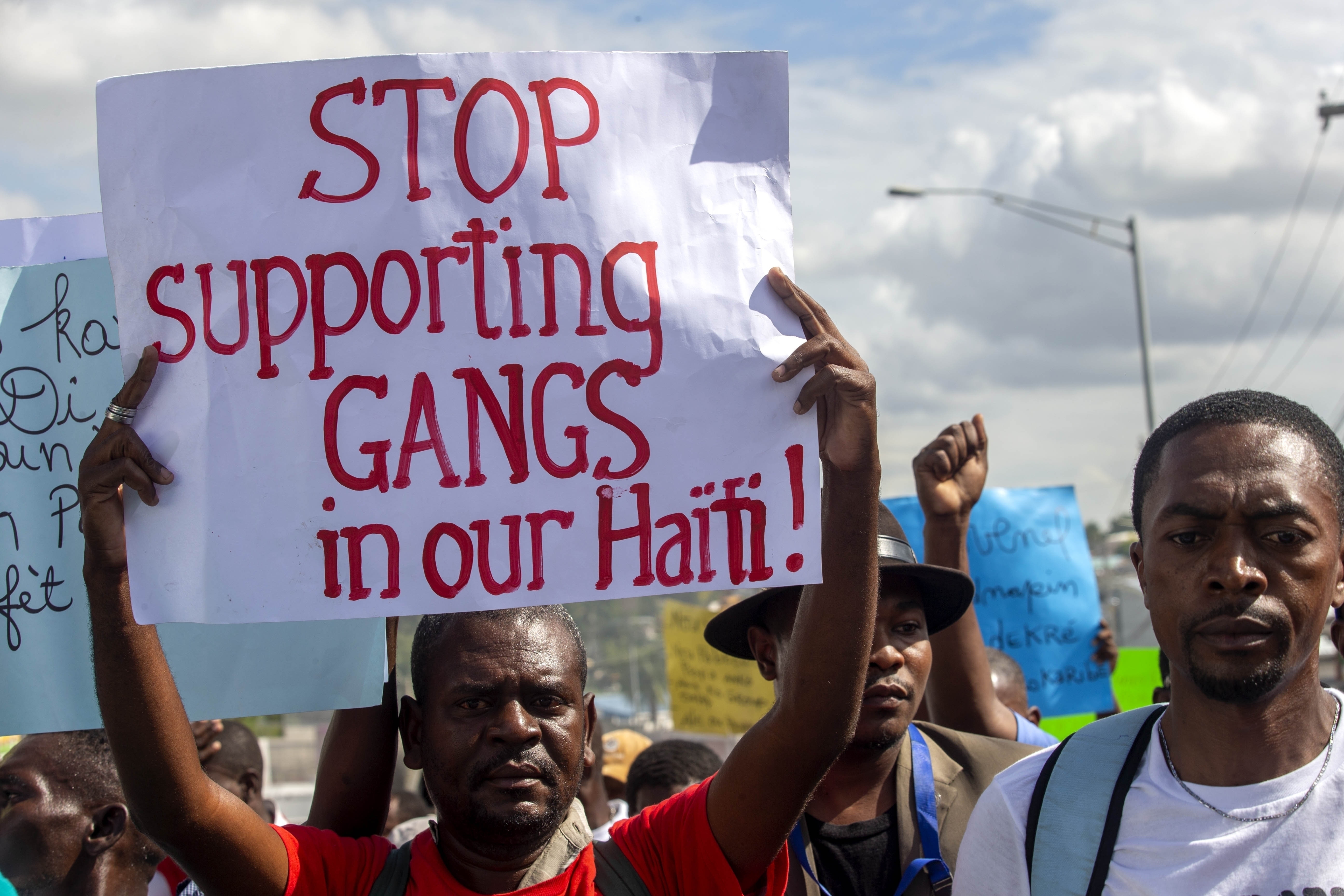 A protester holds a sign demanding an end to supporting gangs, during a protest in Port-au-Prince