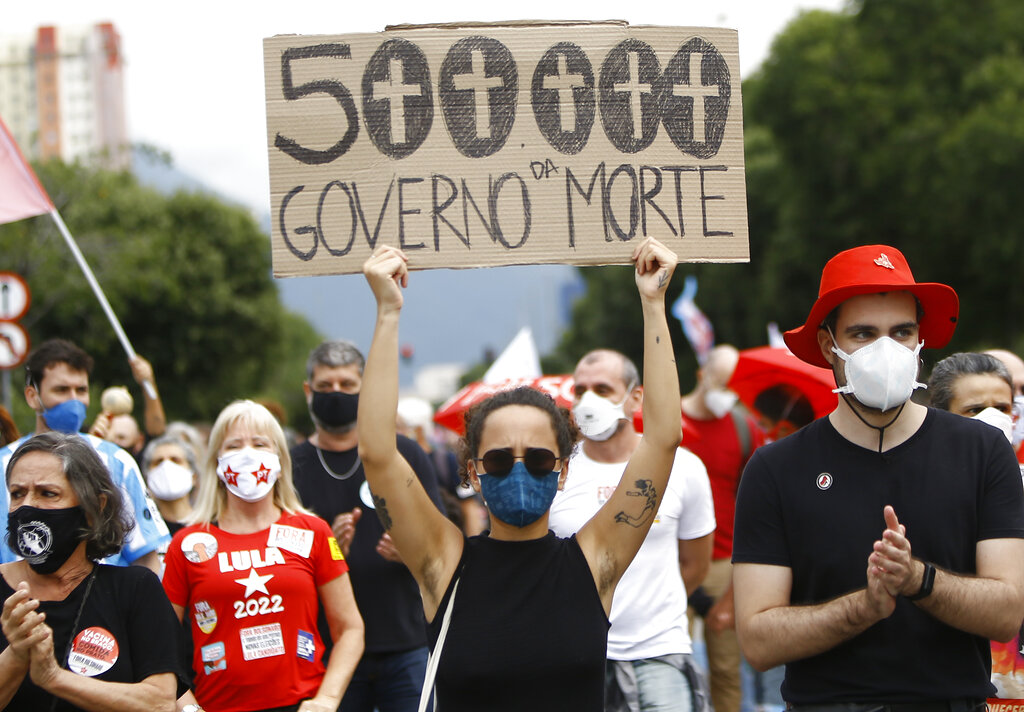 A woman wearing a protective face mask holds a sign with a message that reads in Portuguese; “500,000, government of death” during a protest against Brazilian President Jair Bolsonaro’s handling of the coronavirus pandemic