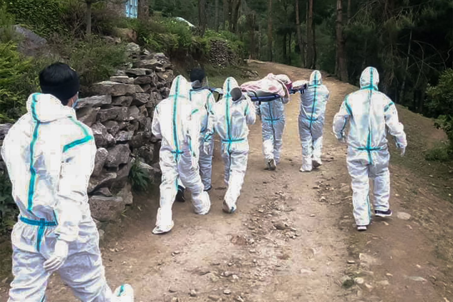 Men in protective gear carry Saraswati Tamang Karki from her home in the village of Monju to the town of Lukla [Courtesy of Silen Bhotiya]