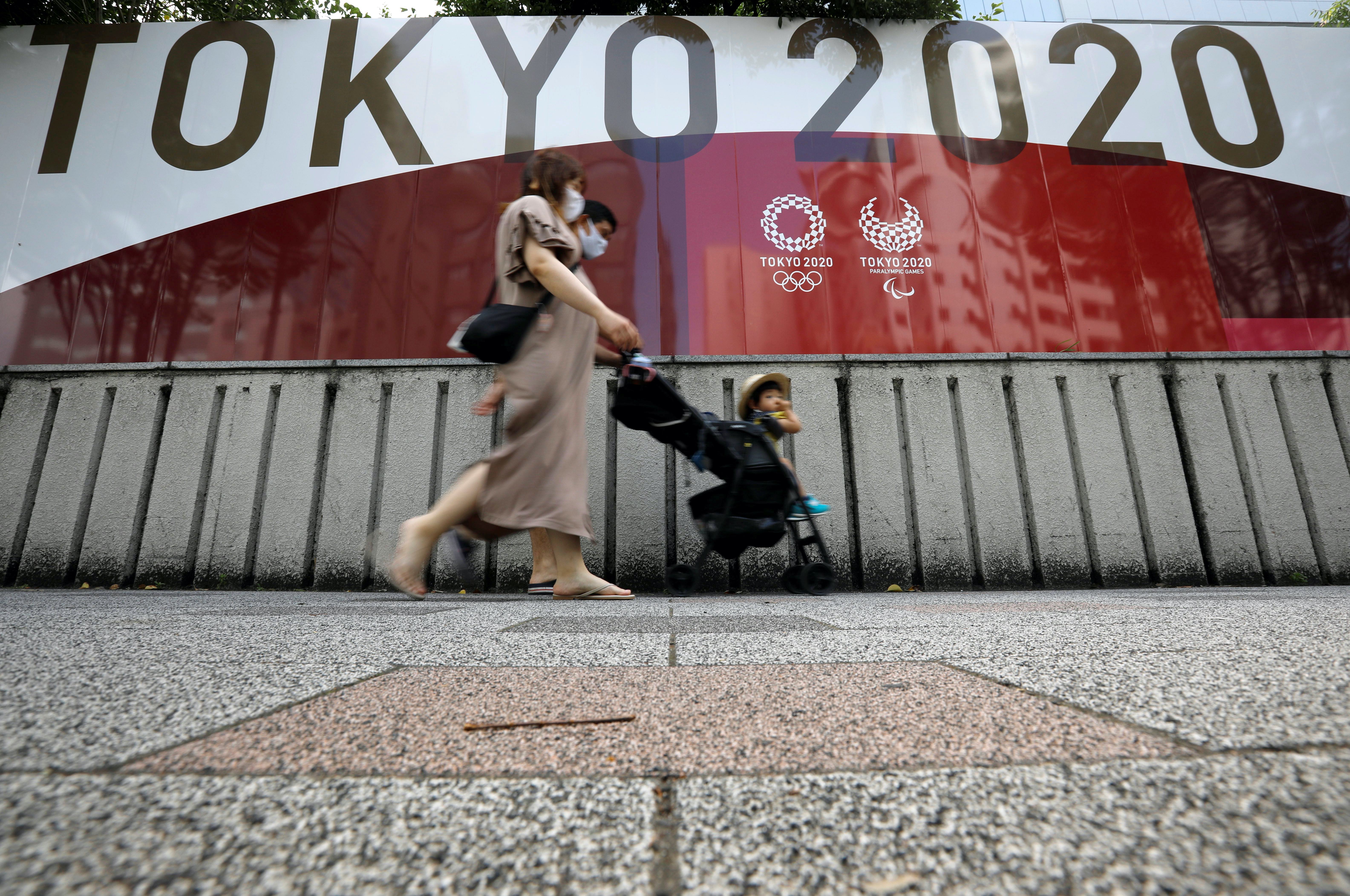 A family walks past an advertisement for the 2020 Olympic and Paralympic Games in Tokyo, Japan
