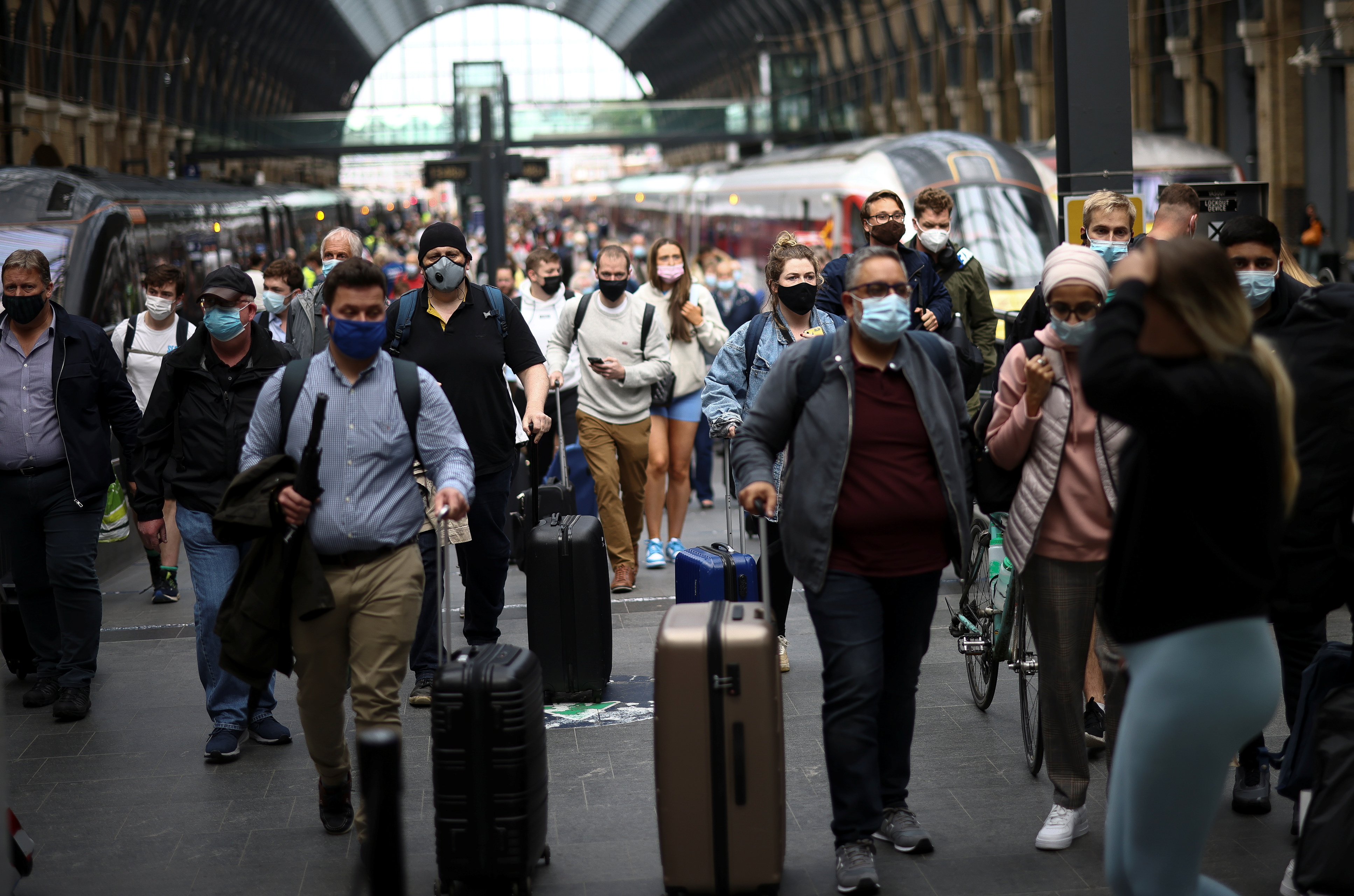 People wearing protective face masks walk along a platform at King’s Cross Station, amid the coronavirus disease (COVID-19) outbreak in London