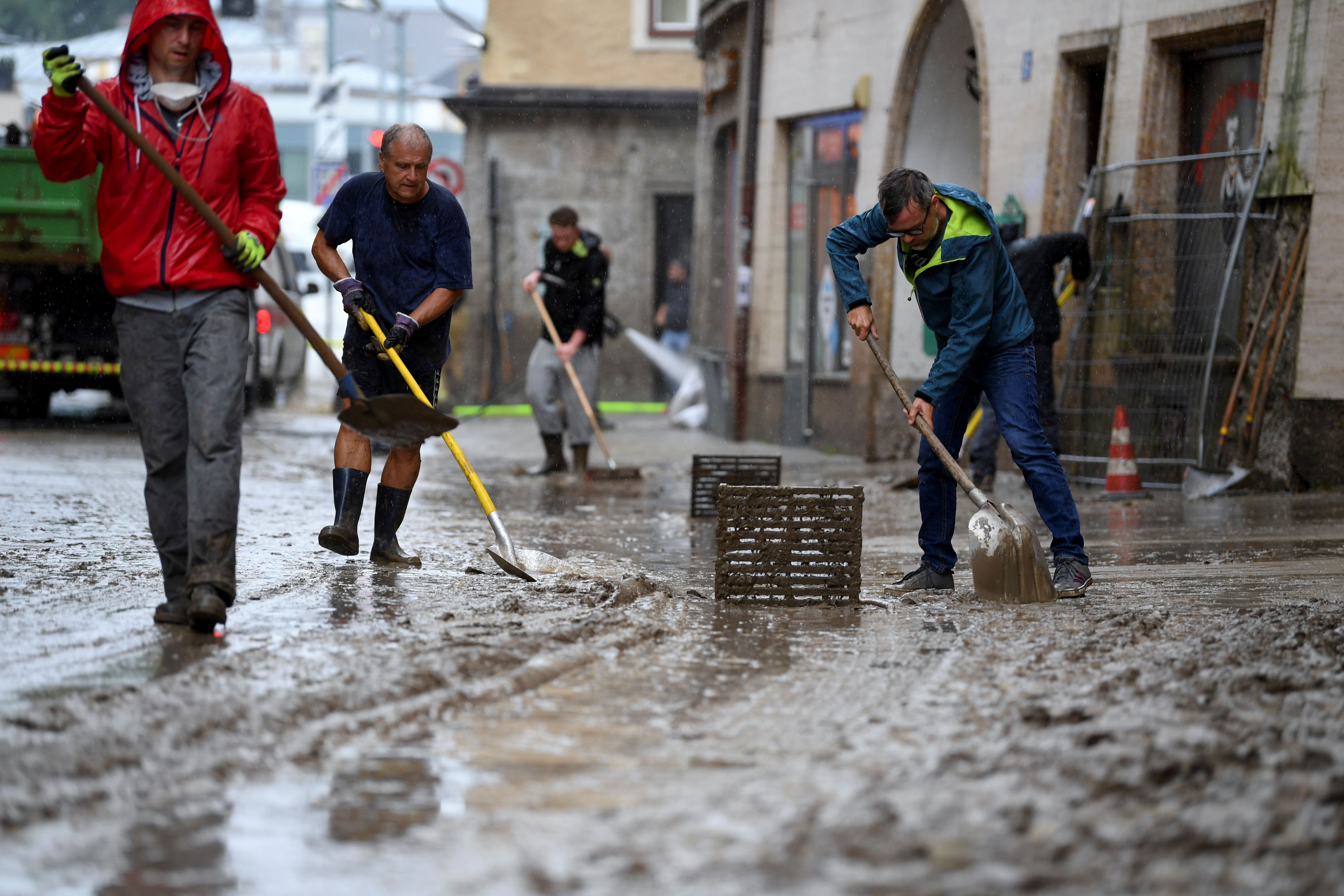 People remove mud after a flood in the city centre of Hallein, Austria