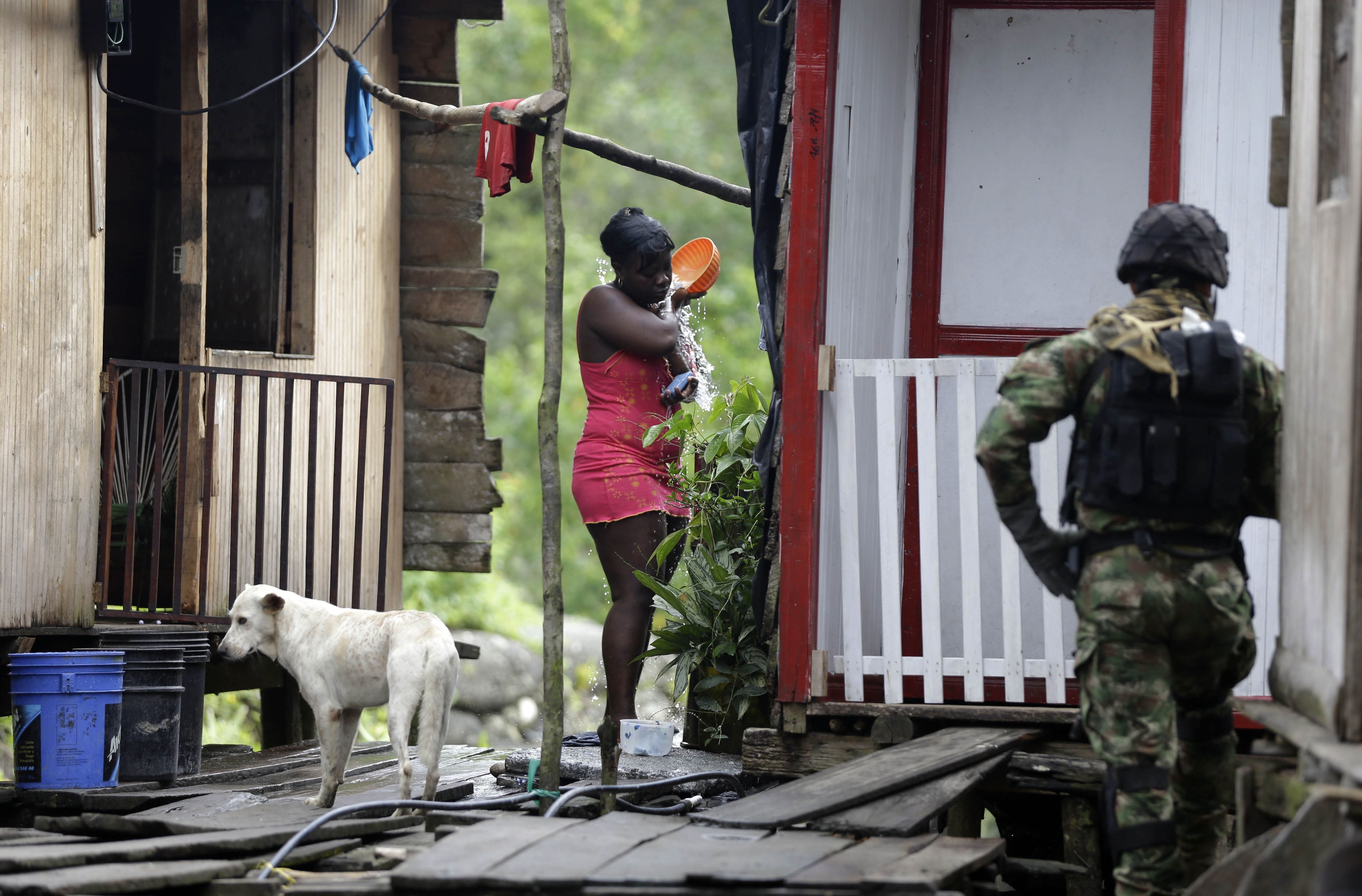 A woman bathes as a Navy Special Forces marine patrols in Buenaventura, March 28, 2014