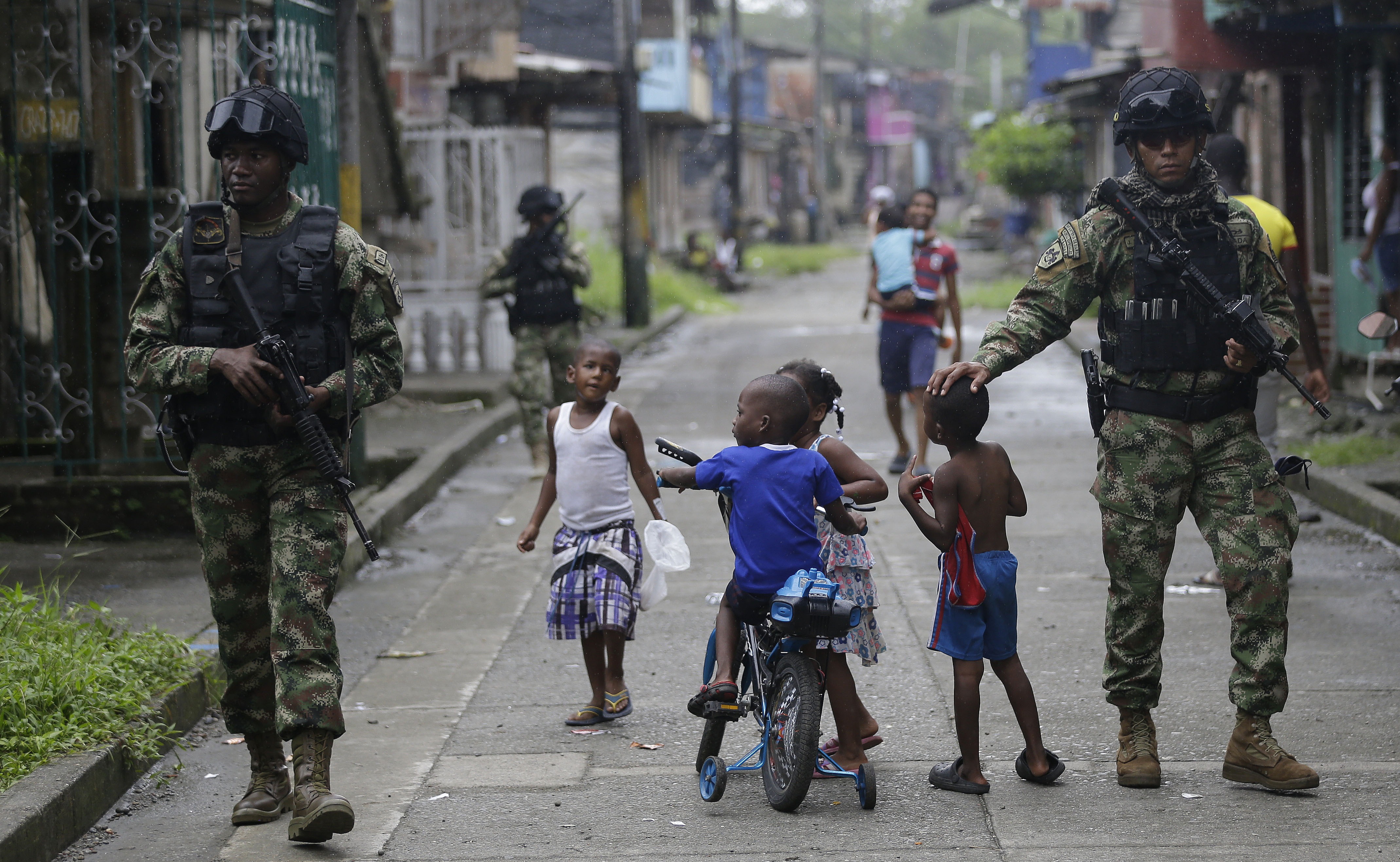 Children play as Navy Special Forces patrol in Buenaventura, March 28, 2014