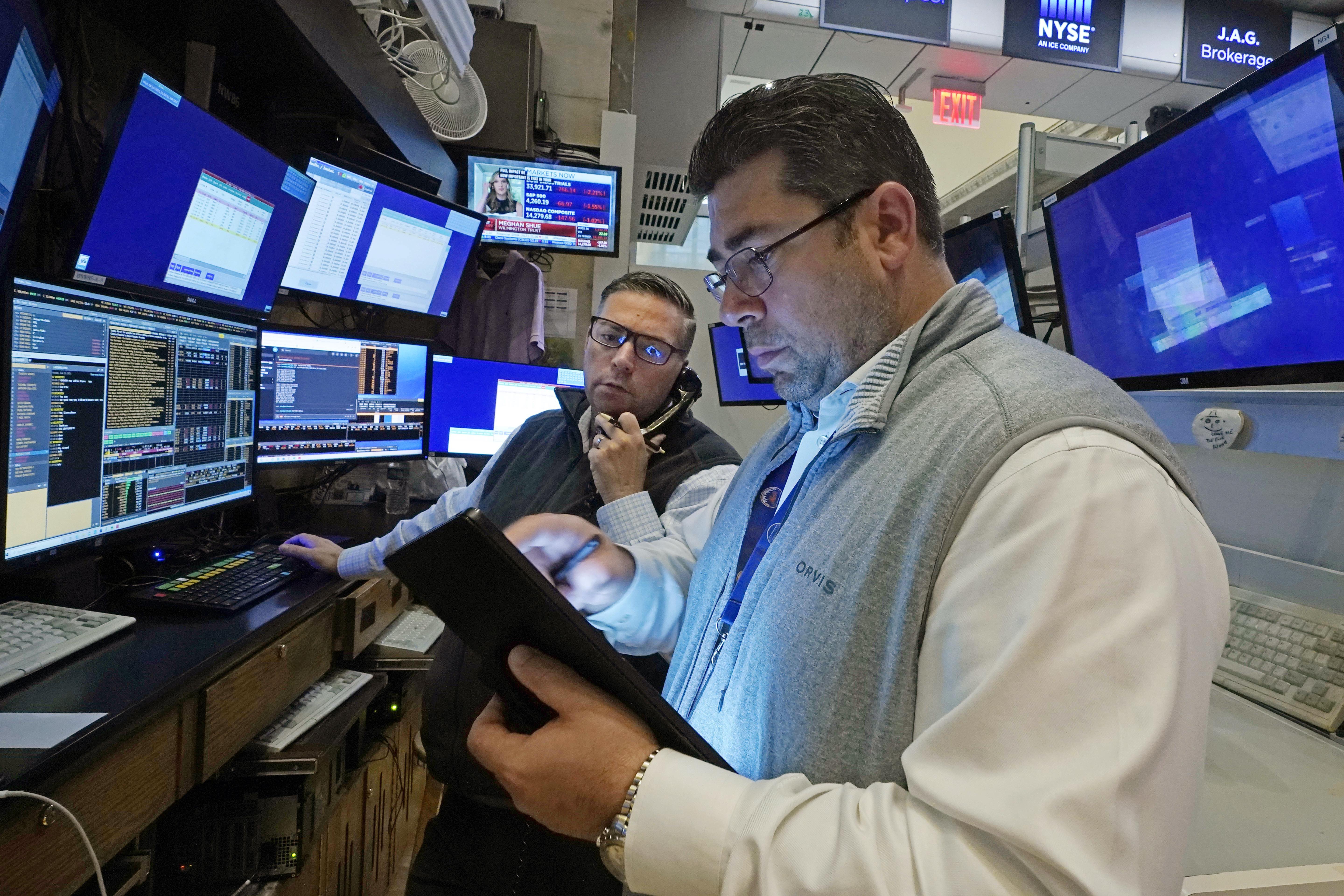 Traders Jonathan Mueller, left, and Michael Capolino work on the floor of the New York Stock Exchange on Monday