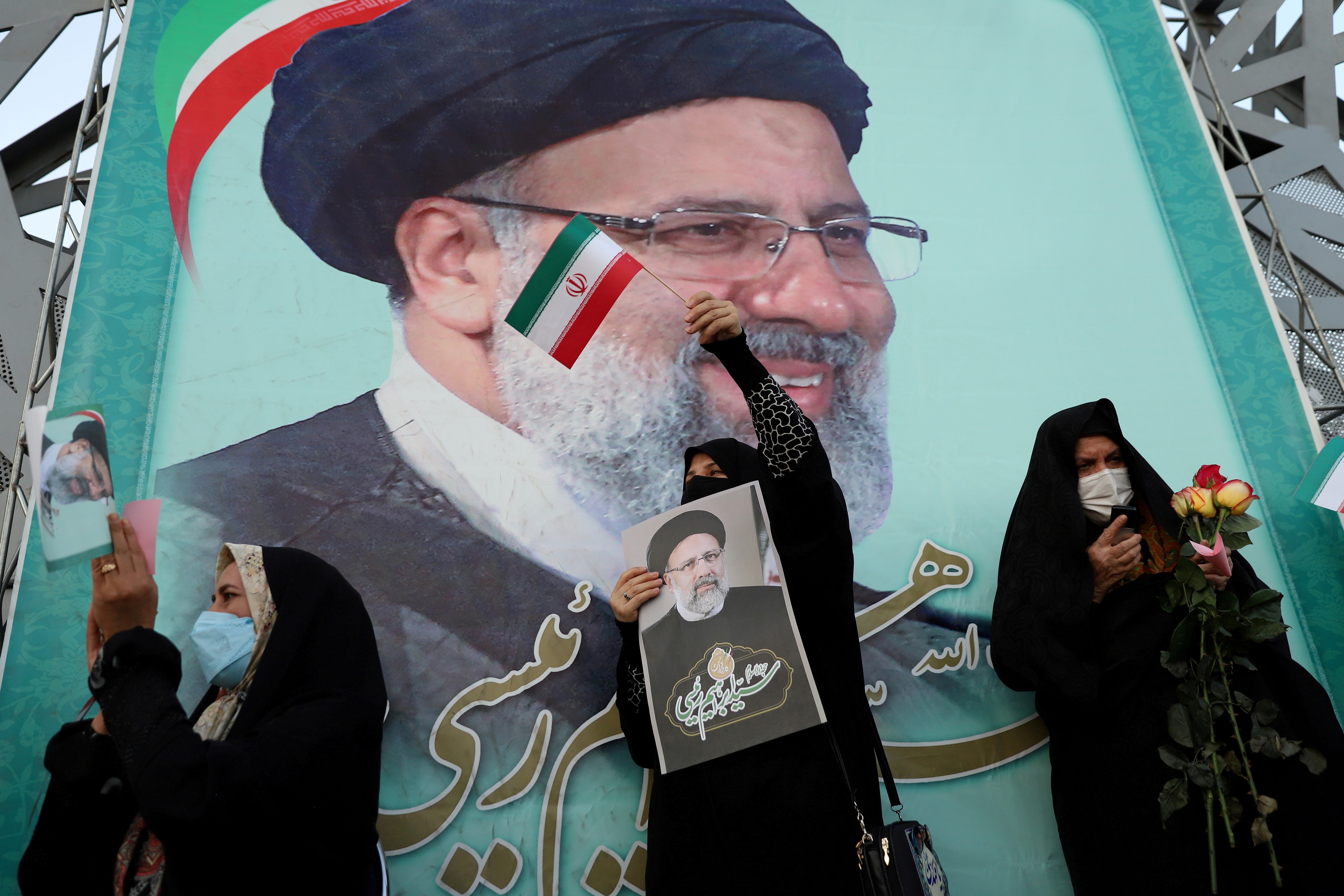 Supporters of newly inaugurated Iranian President Ebrahim Raisi display his portrait during a celebratory rally for his presidential election victory [File: Majid Asgaripour/West Asia News Agency via Reuters]