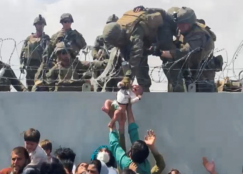 FILE PHOTO: A baby is handed over to the American army over the perimeter wall of the airport for it to be evacuated, in Kabul, Afghanistan, August 19, 2021. OMAR HAIDARI/via REUTERS/File Photo/File Photo