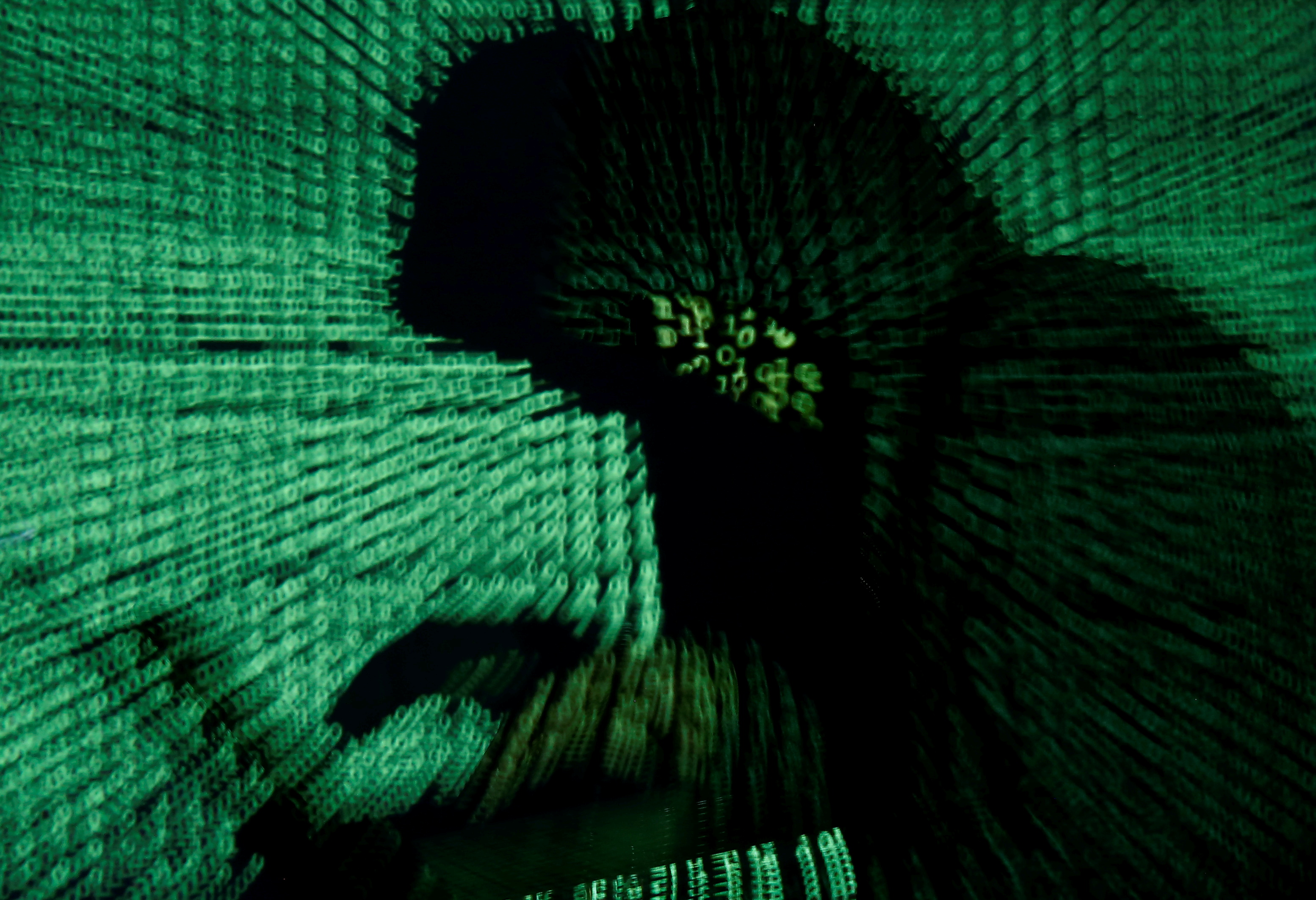 A man is seen holding a laptop computer as cyber code is projected on him