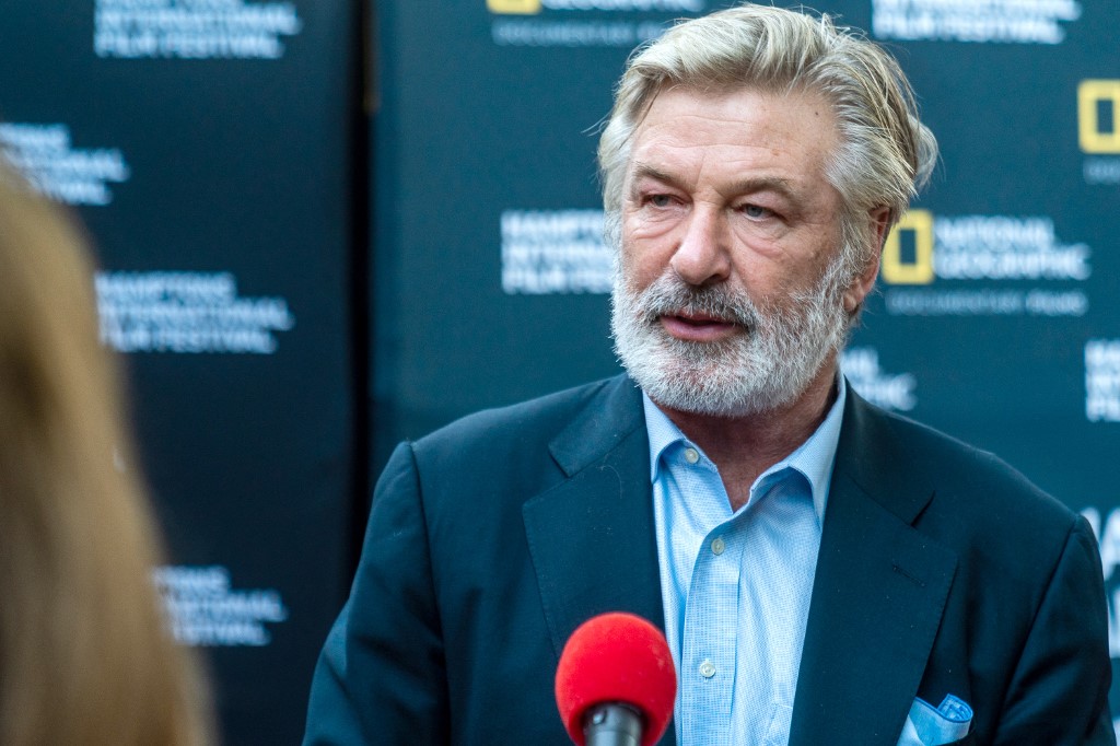 Alec Baldwin in front of a microphone at a film festival.