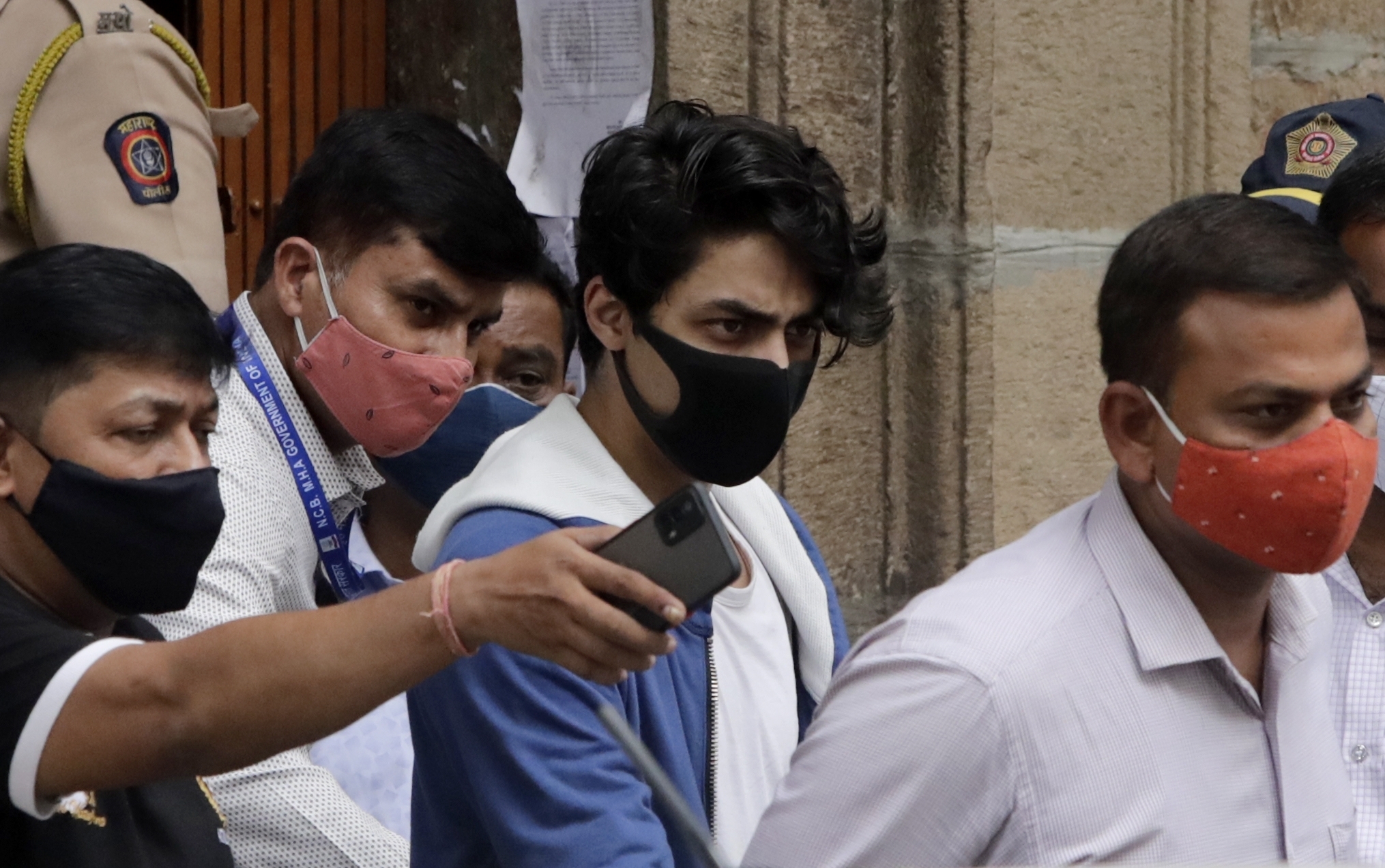 Bollywood actor Shah Rukh Khan's son Aryan Khan, center, escorted by law enforcement officials
