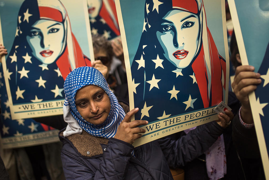 Woman in hijab carries poster