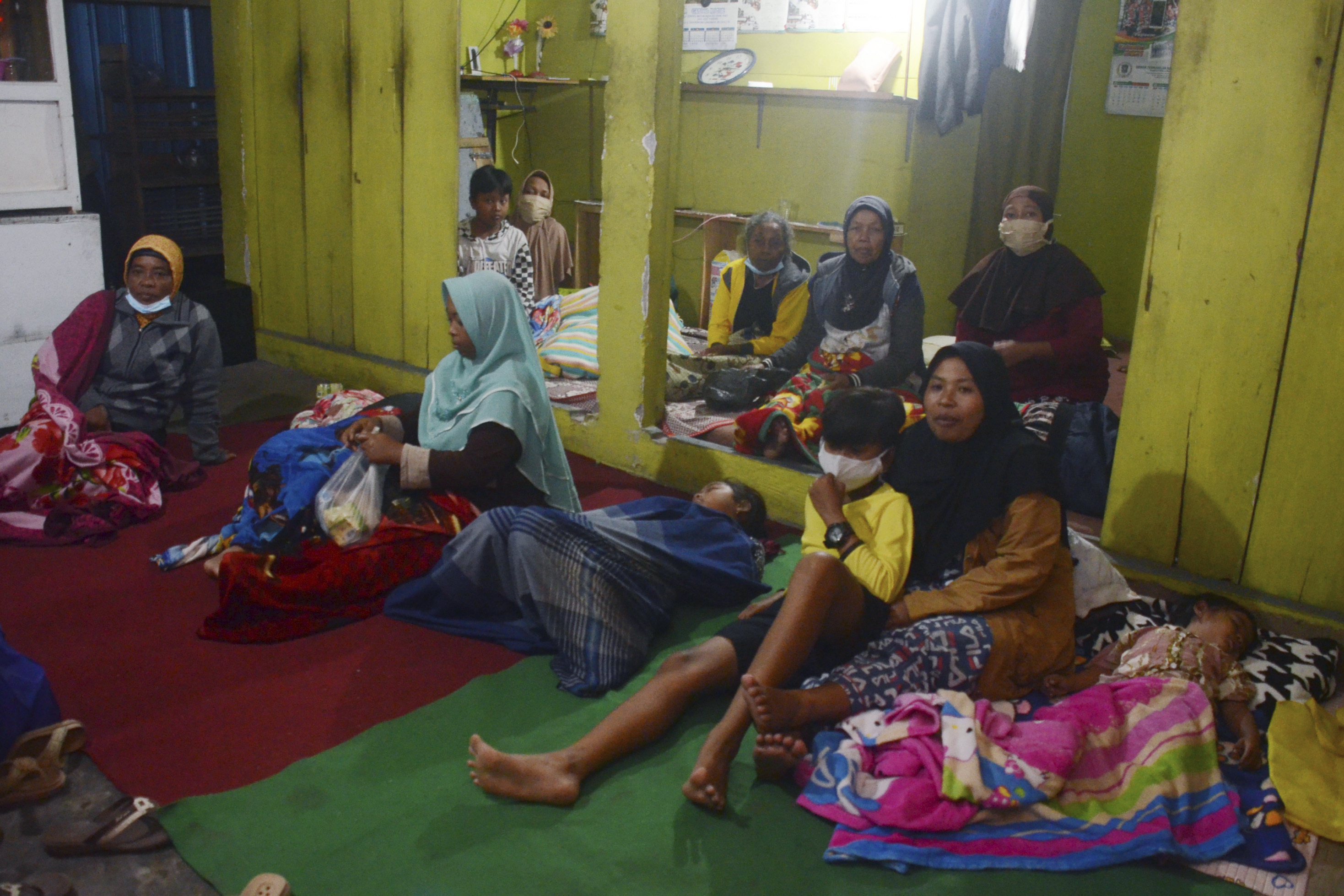 Villagers rest at a temporary shelter after evacuating their homes following the eruption of Mount Semeru