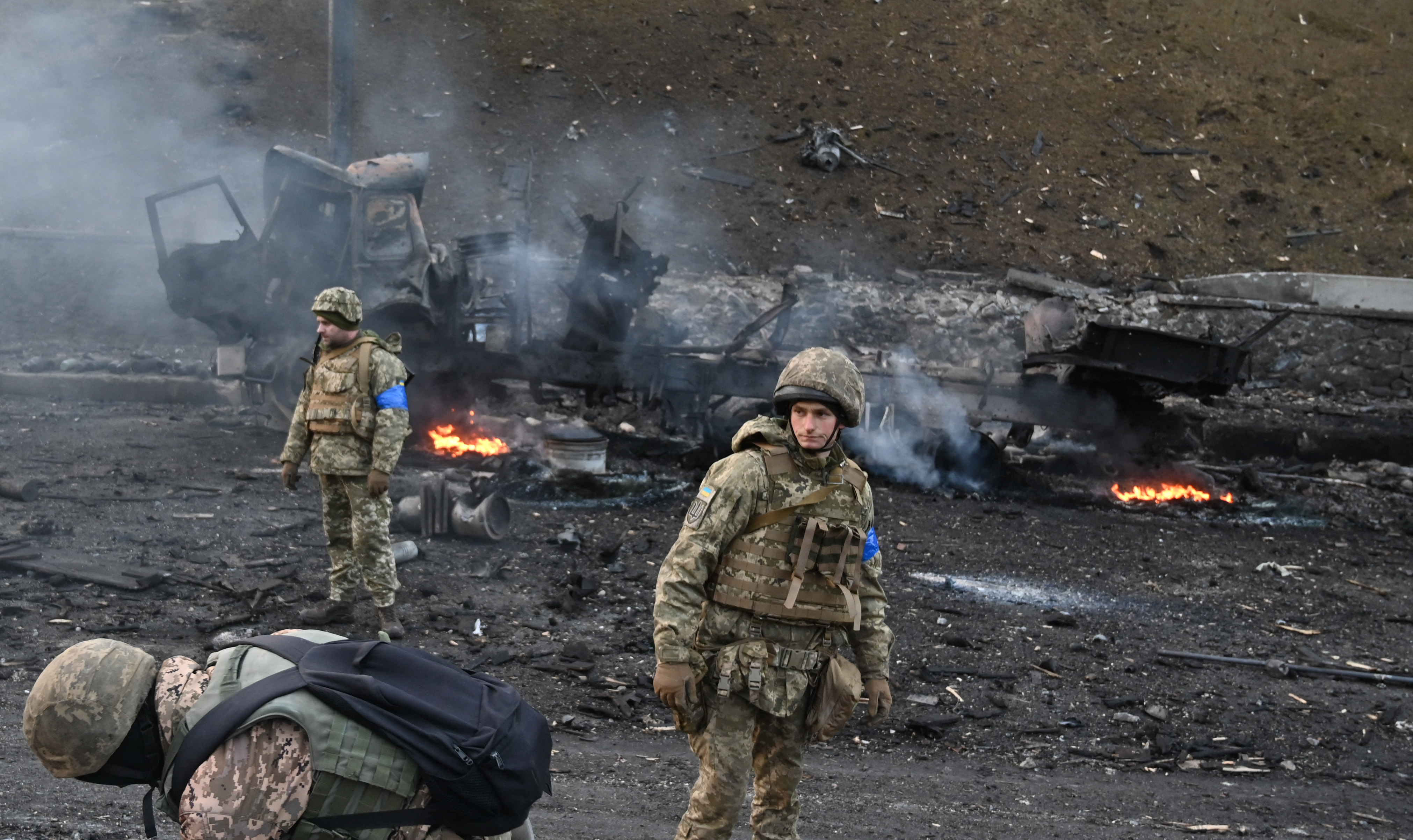 Ukrainian service members look for unexploded shells after fighting with Russian raiding group in Kyiv.