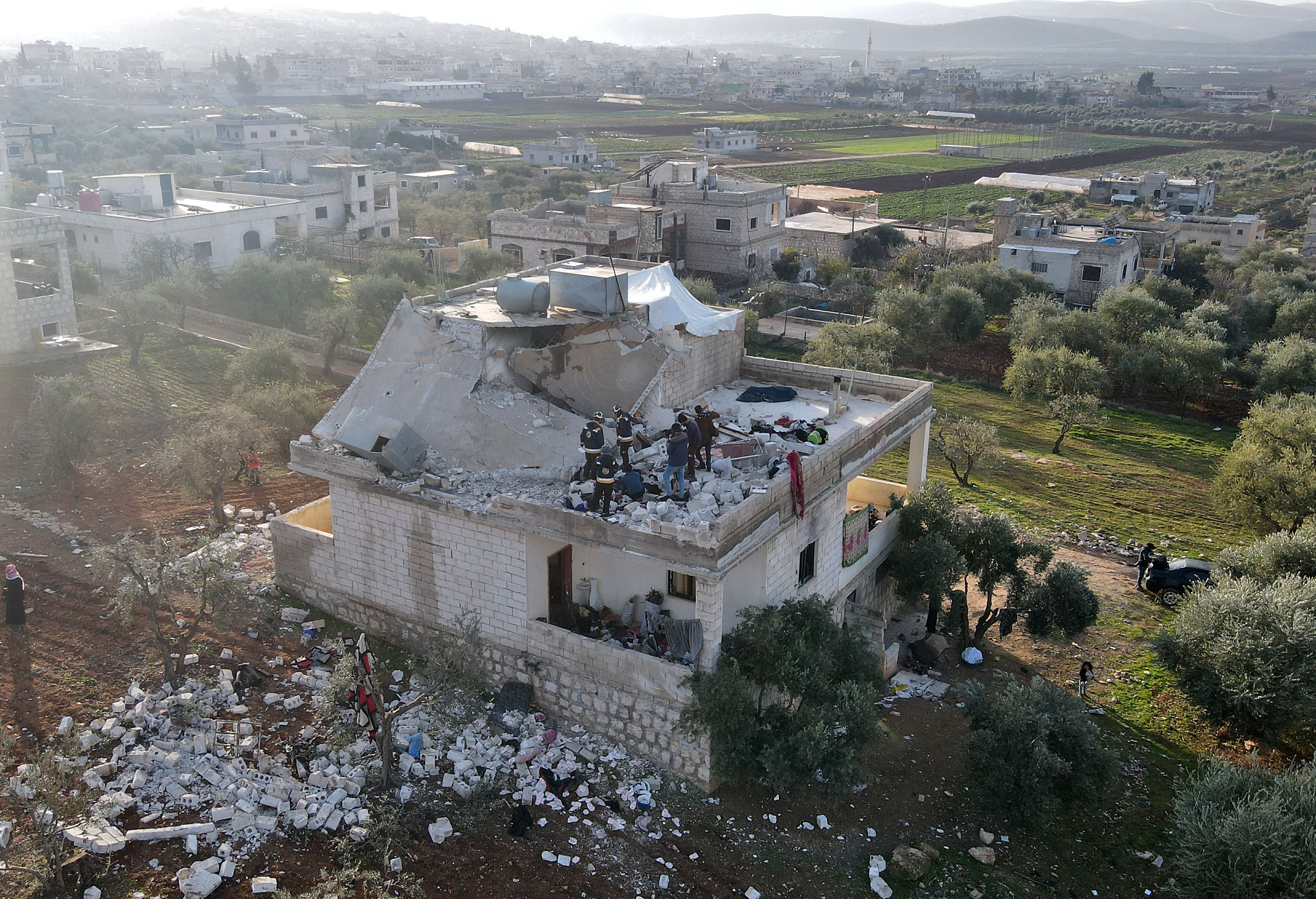 Syrians gather on February 3, 2022 at the scene following an overnight raid by US special operations forces against suspected jihadists in northwestern Syria which left at least nine people dead, including three civilians.