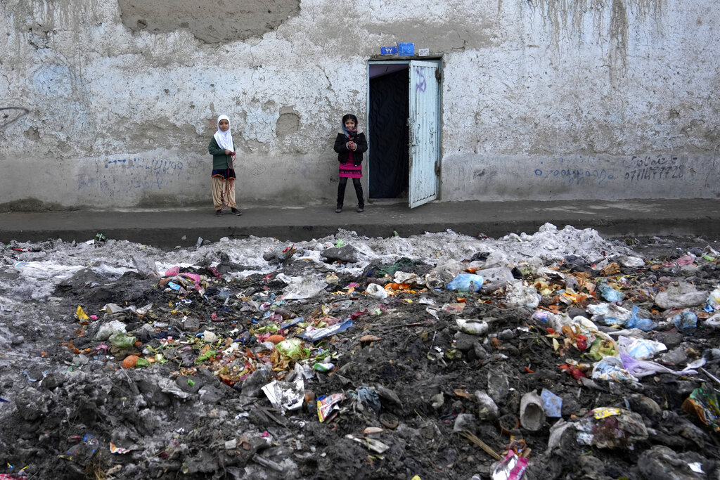 Two young girls stand outside their house in Kabul, Afghanistan.