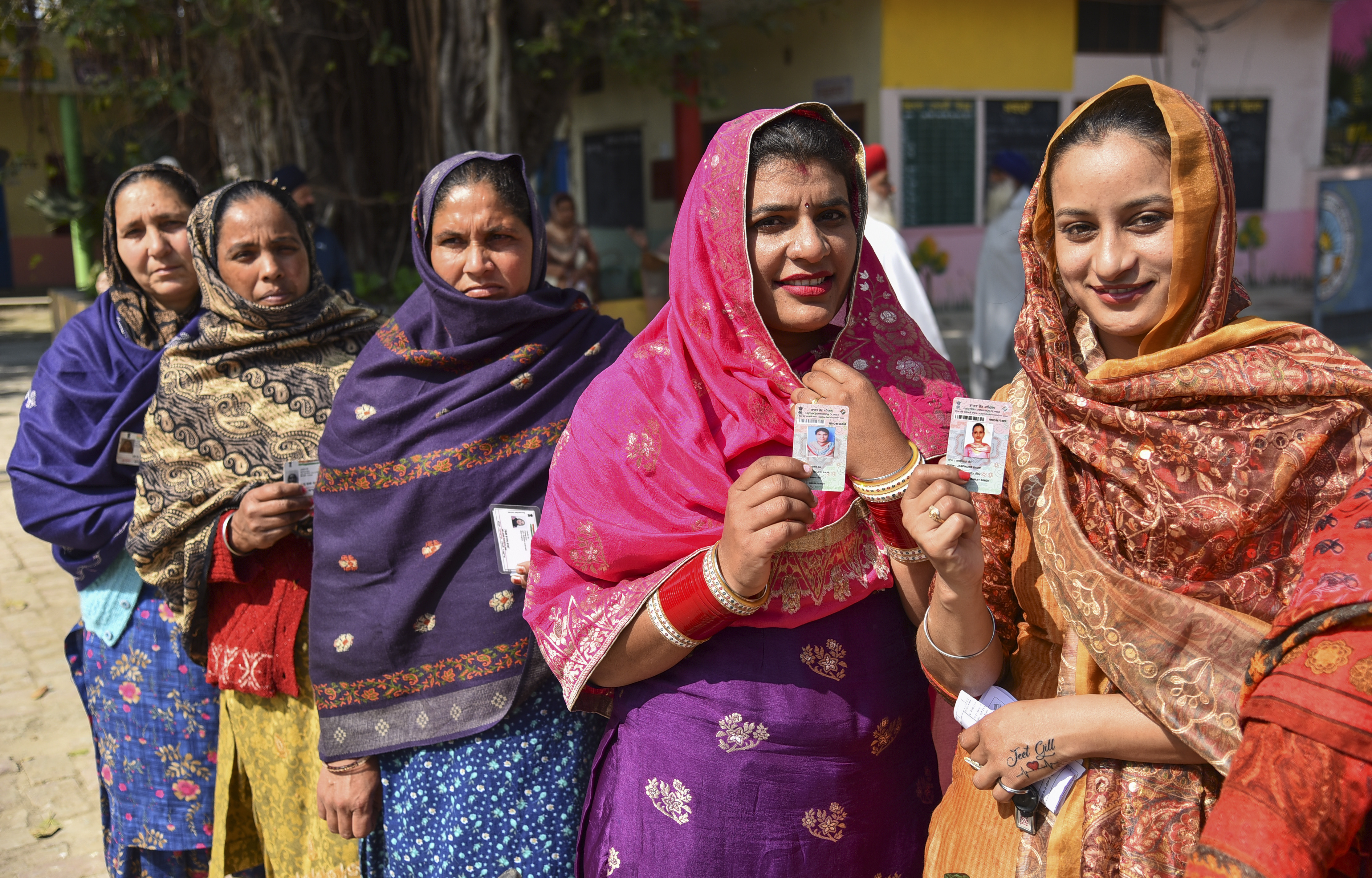 Village women display their voter identity cards as they arrive to cast their votes for the Punjab State Assembly elections