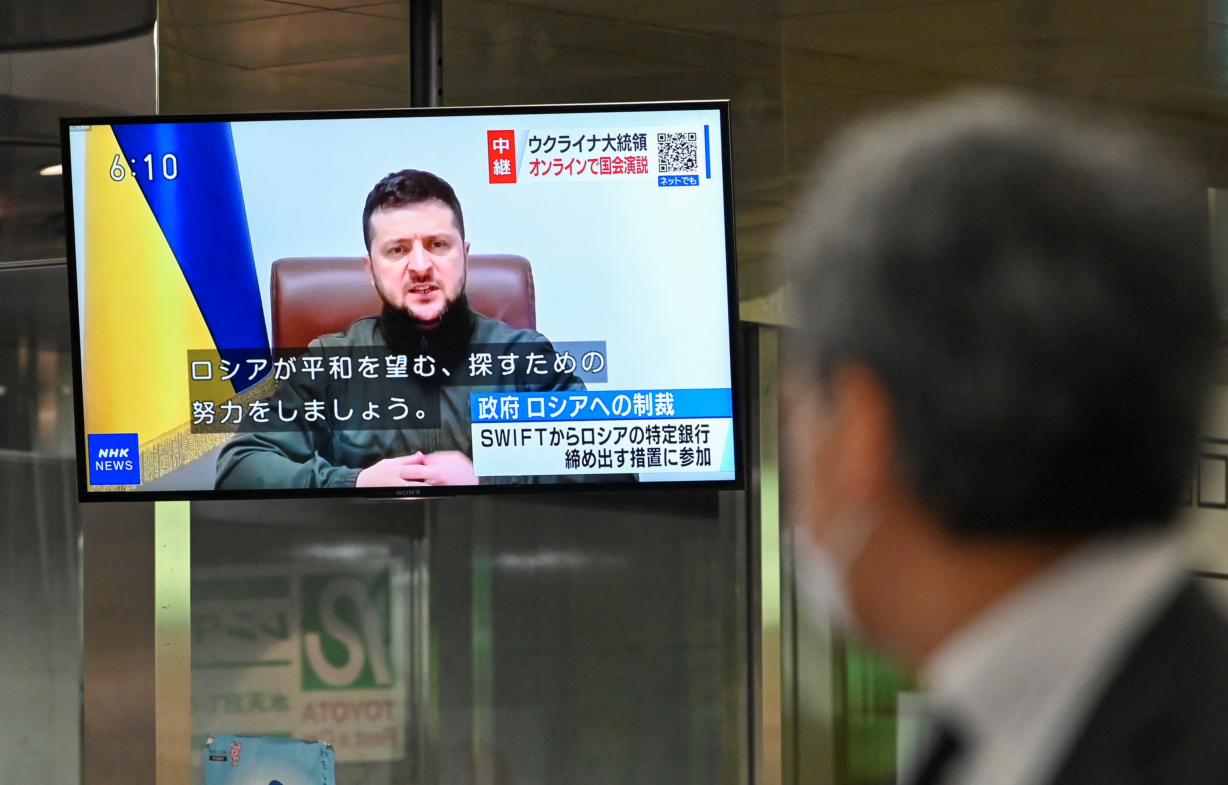 Pedestrian looks at broadcast of Ukrainian President Volodymyr Zelenskyy delivering a virtual address to Japan's parliament in Tokyo