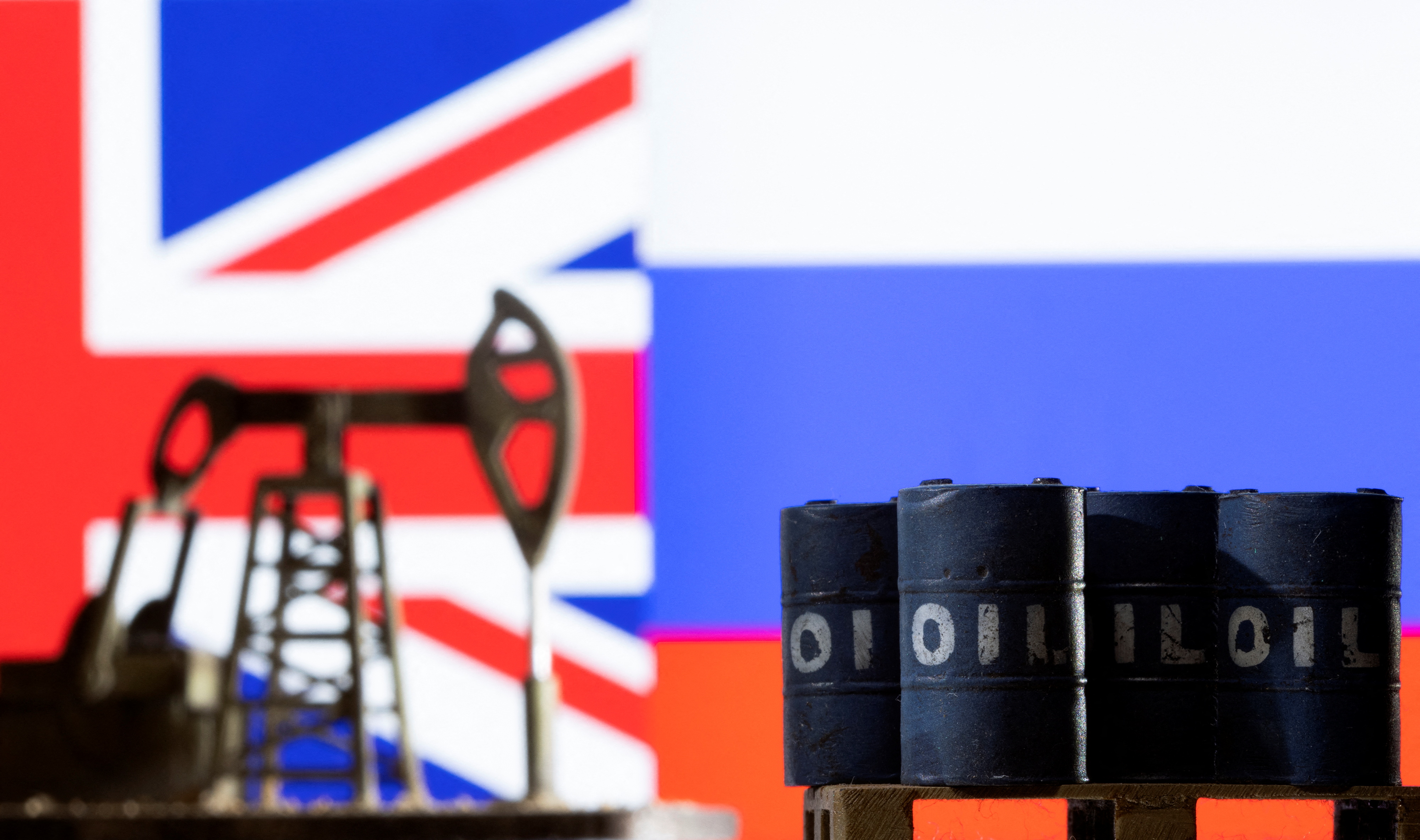 Models of pump jack and oil barrels are seen in front of the displayed UK and Russia flag colour