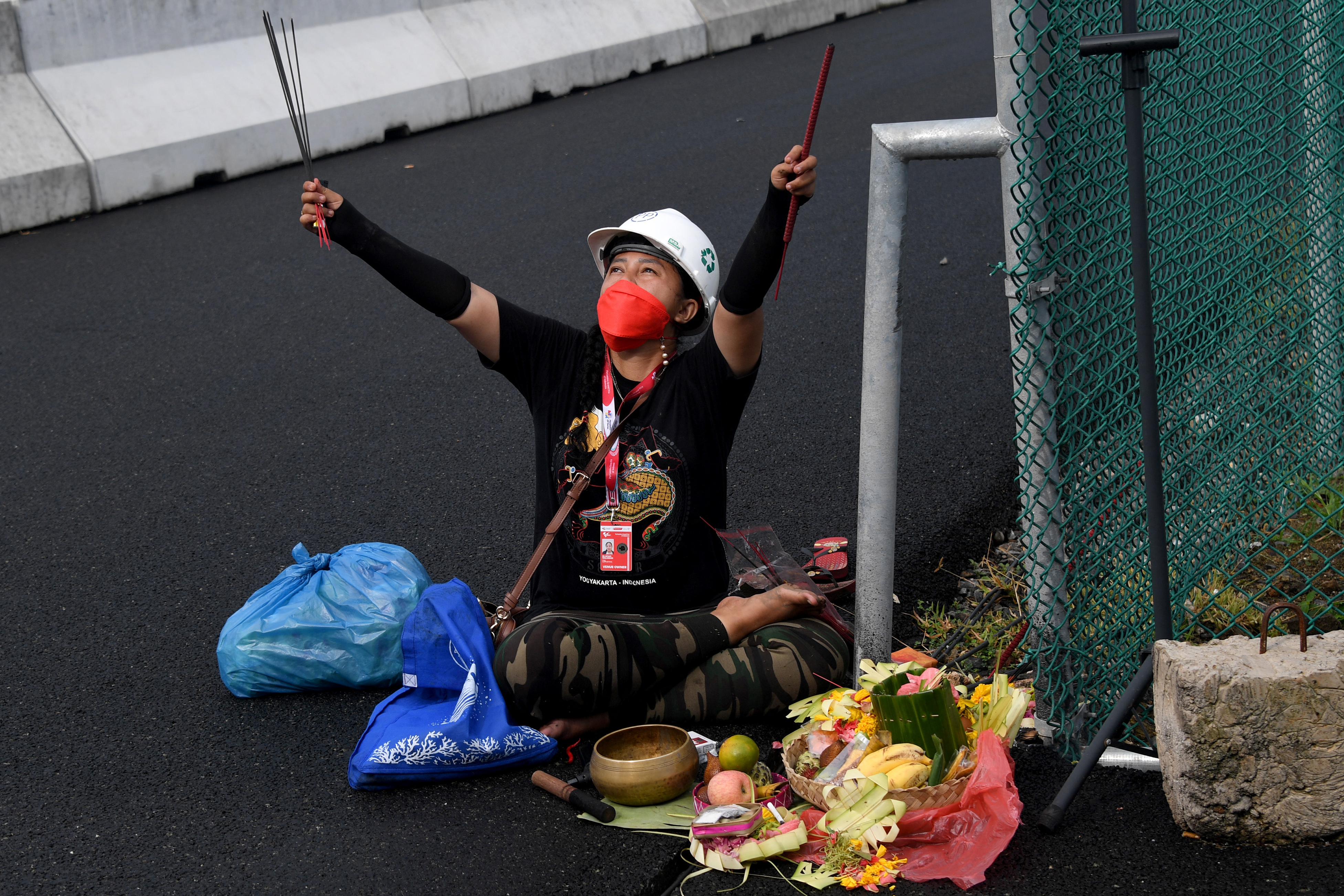 Rara Istiati Wulandari conducts a ceremony for good weather on the side of the Mandalika track with an array of offerings including cigarettes and fruit