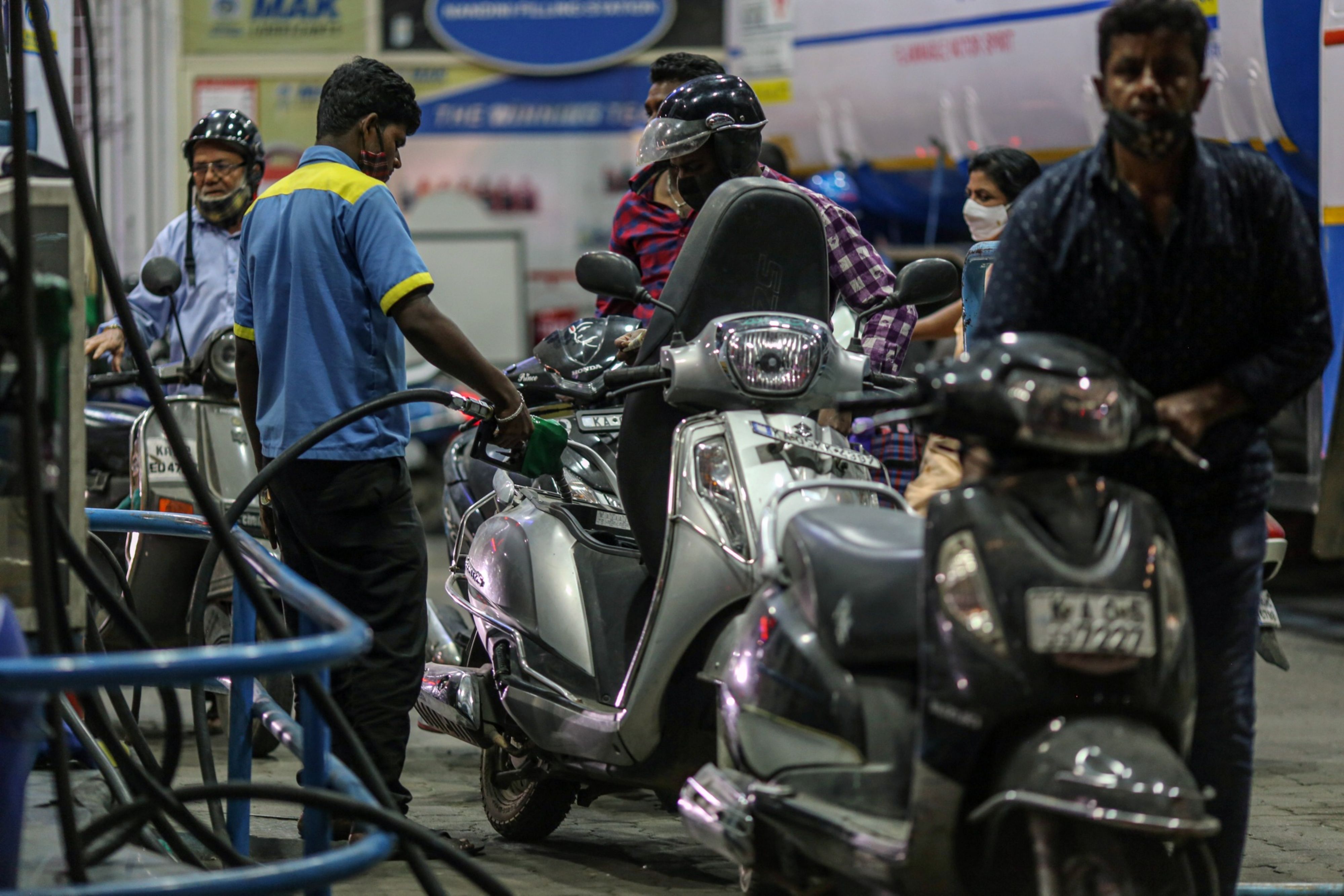 An attendant refuels a customer's motorcycle at a gas station in Bengaluru, India.