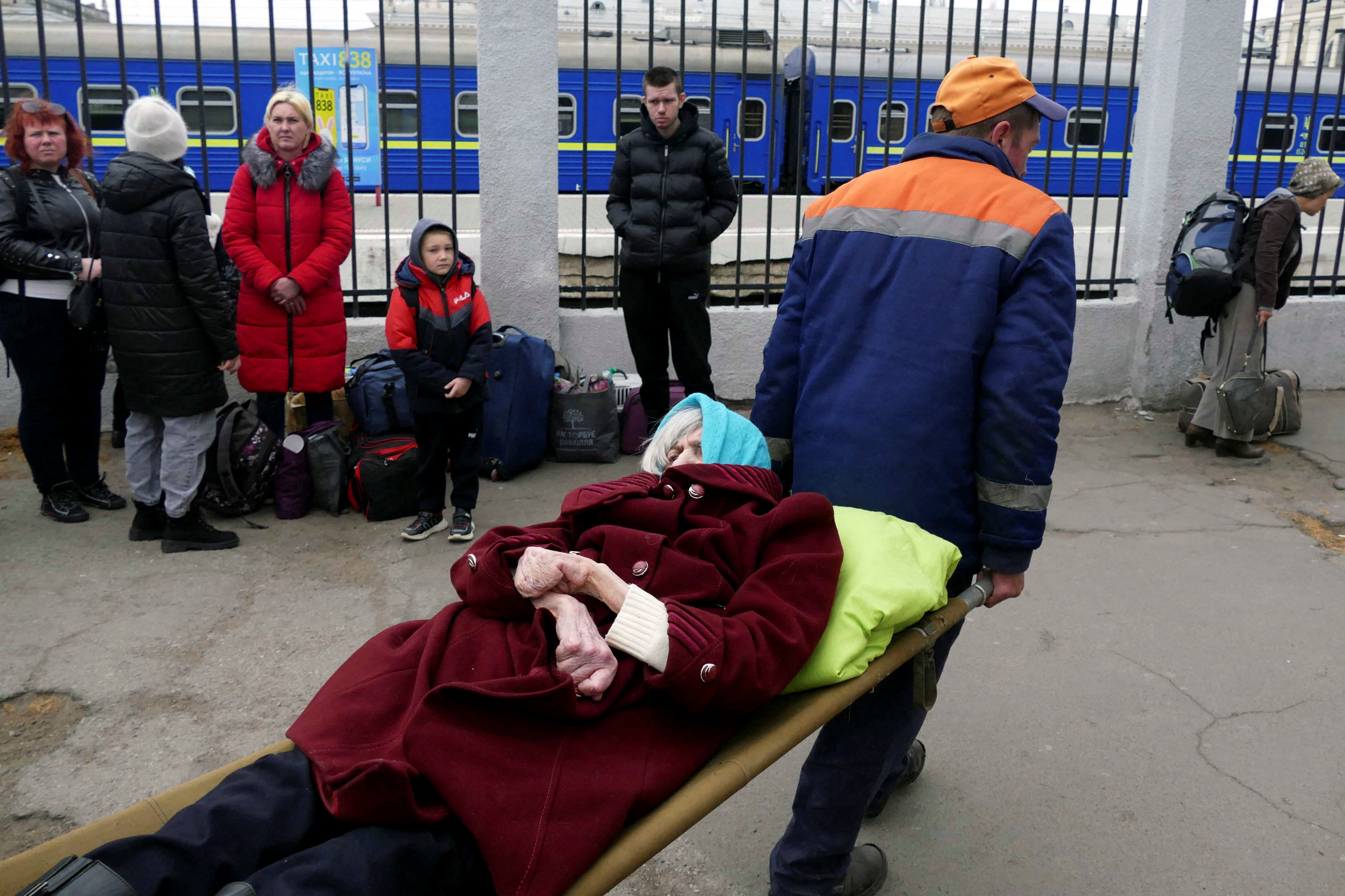 Men carry an elderly woman as residents from Mykolaiv arrive by bus in Odesa, after being evacuated following shelling. 