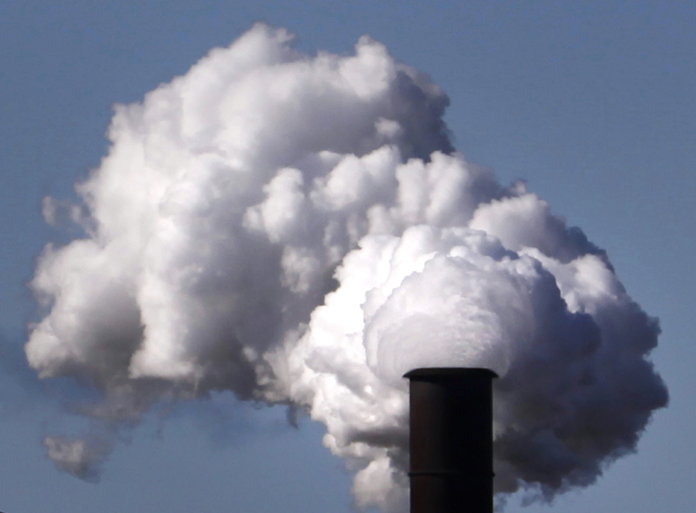 An industrial chimney is billowing what seems like smoke.