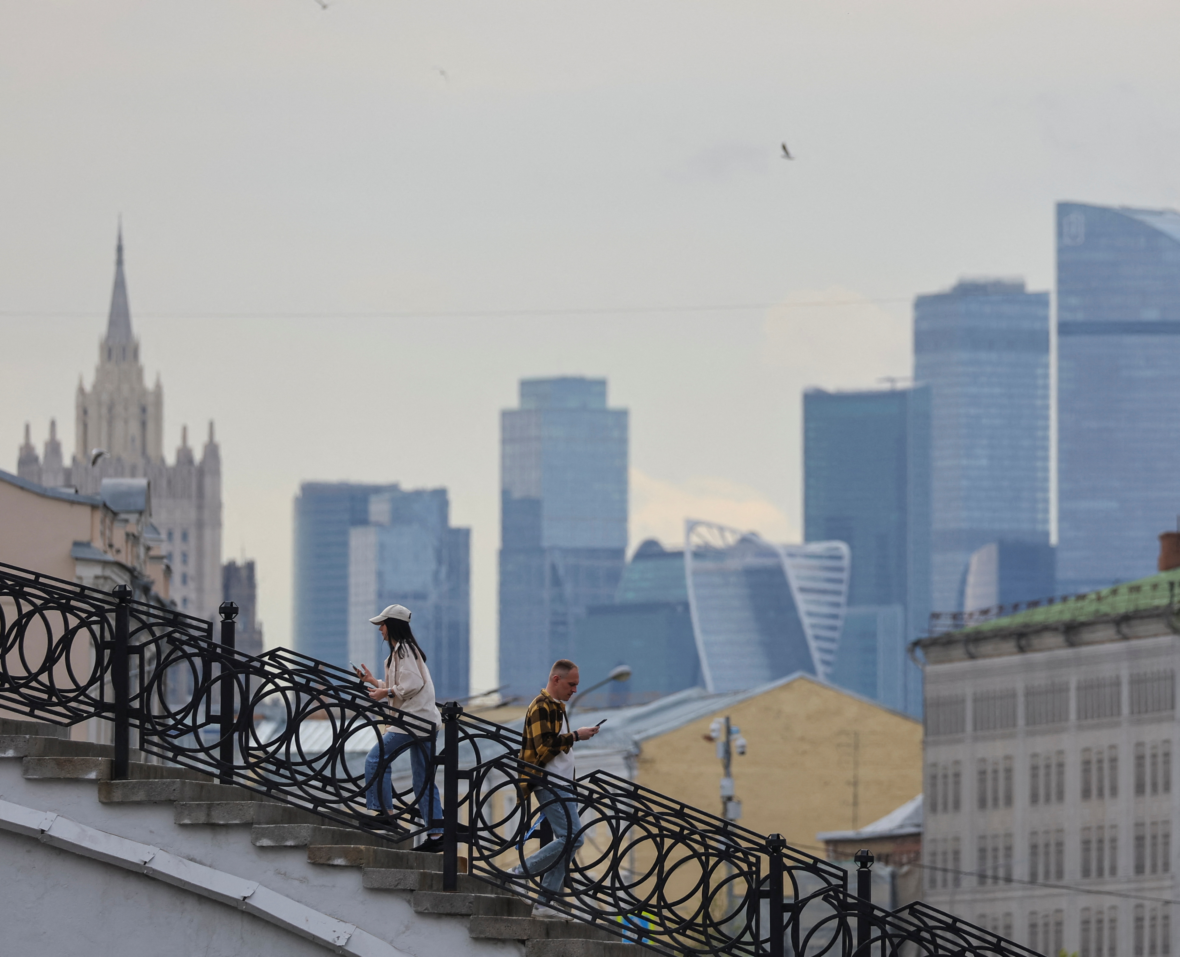 People walk along at the bridge, with the Moscow International Business Centre also known as "Moskva-City" seen in the background in Moscow, Russia