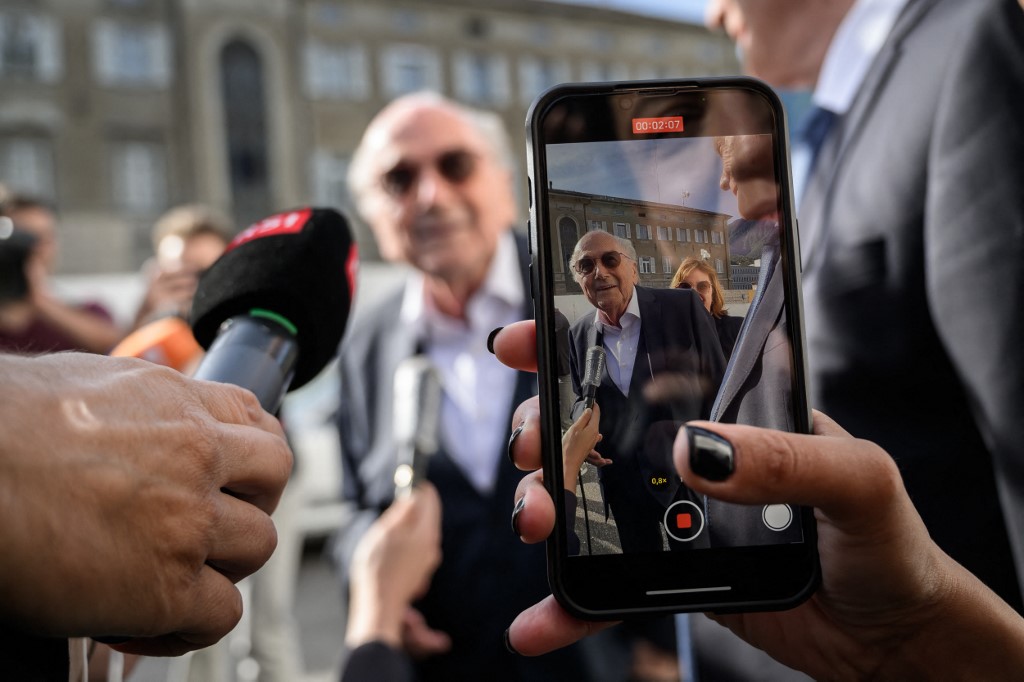Former FIFA president Sepp Blatter is seen on a phone screen as he arrives to Switzerland's Federal Criminal Court for the start of his trial