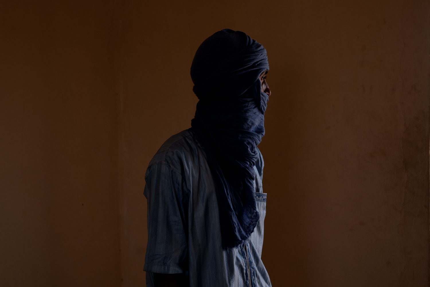 Ag poses for a portrait in an office in Mbera camp recalling his journey fleeing violence in Mali 