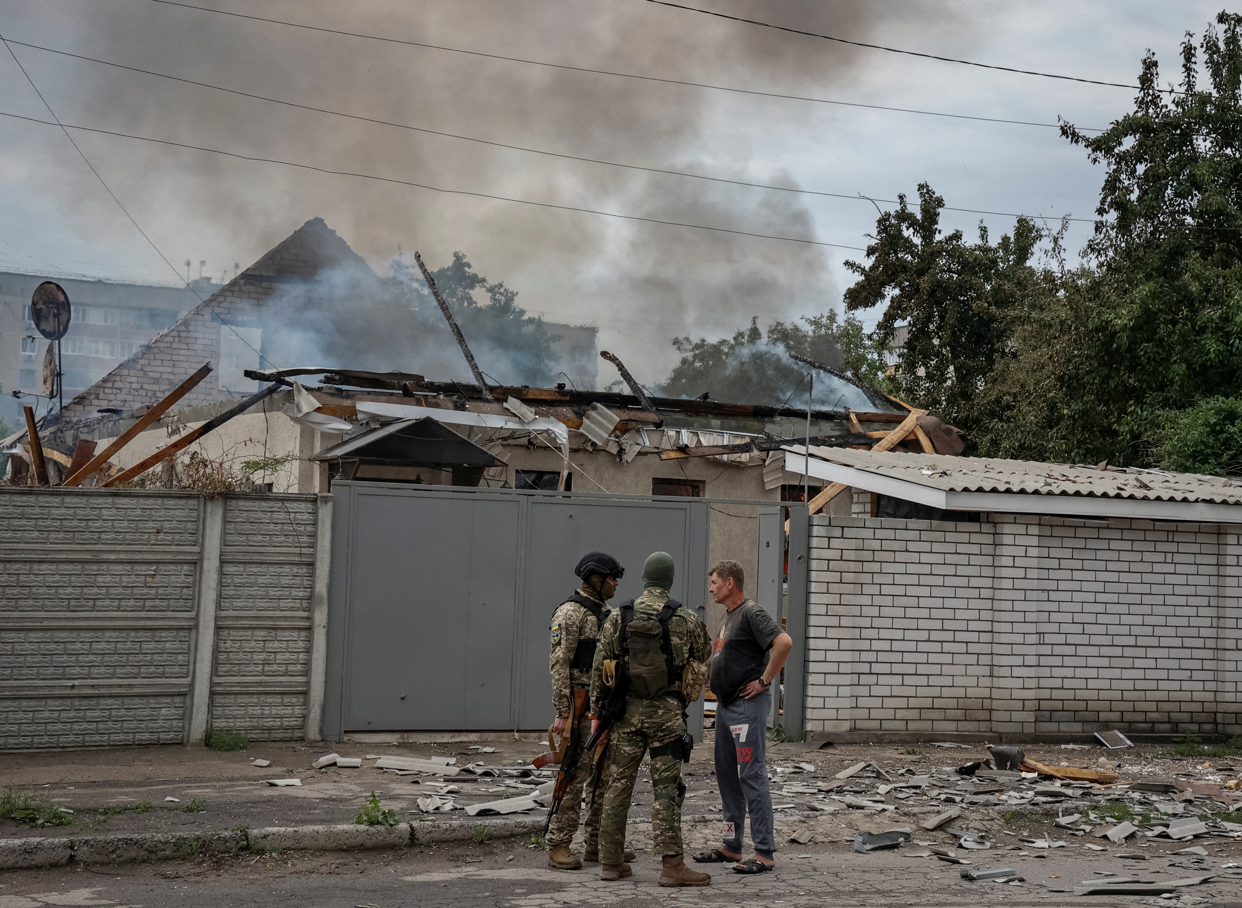 Police officers speak with a local resident as his house burns following shelling, as Russia's attack on Ukraine continues, in Lysychansk, Luhansk region Ukraine June 2, 2022