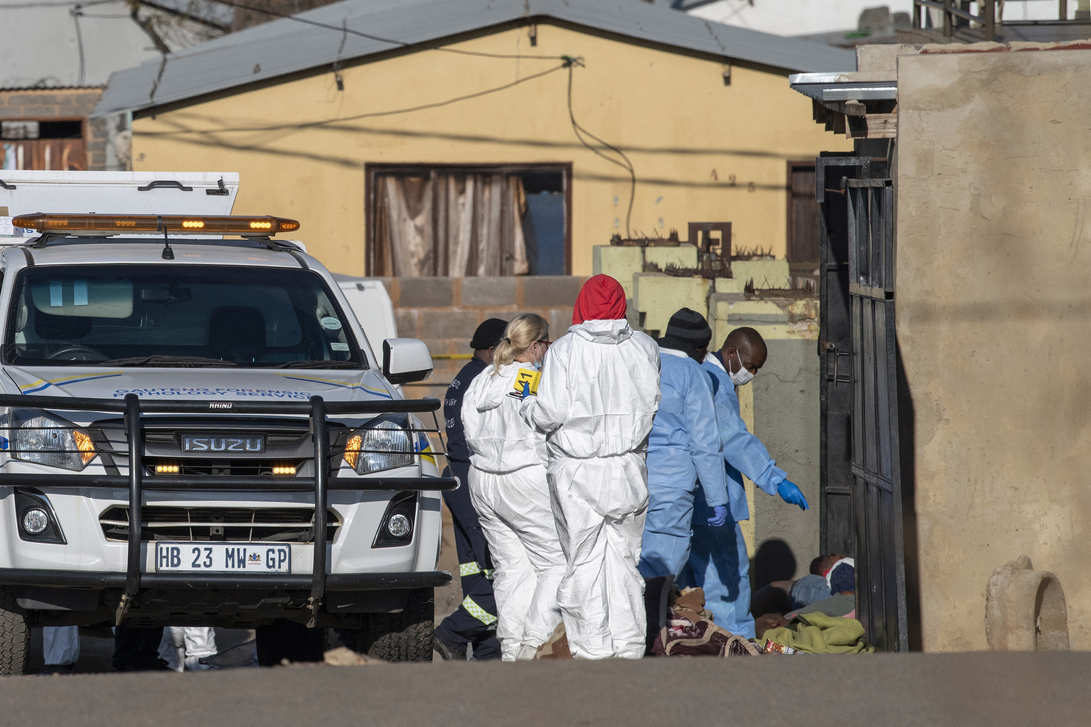 Members of the South African Police Service (SAPS) and forensic pathology service inspect the scene of a mass shooting in Soweto, South Africa,