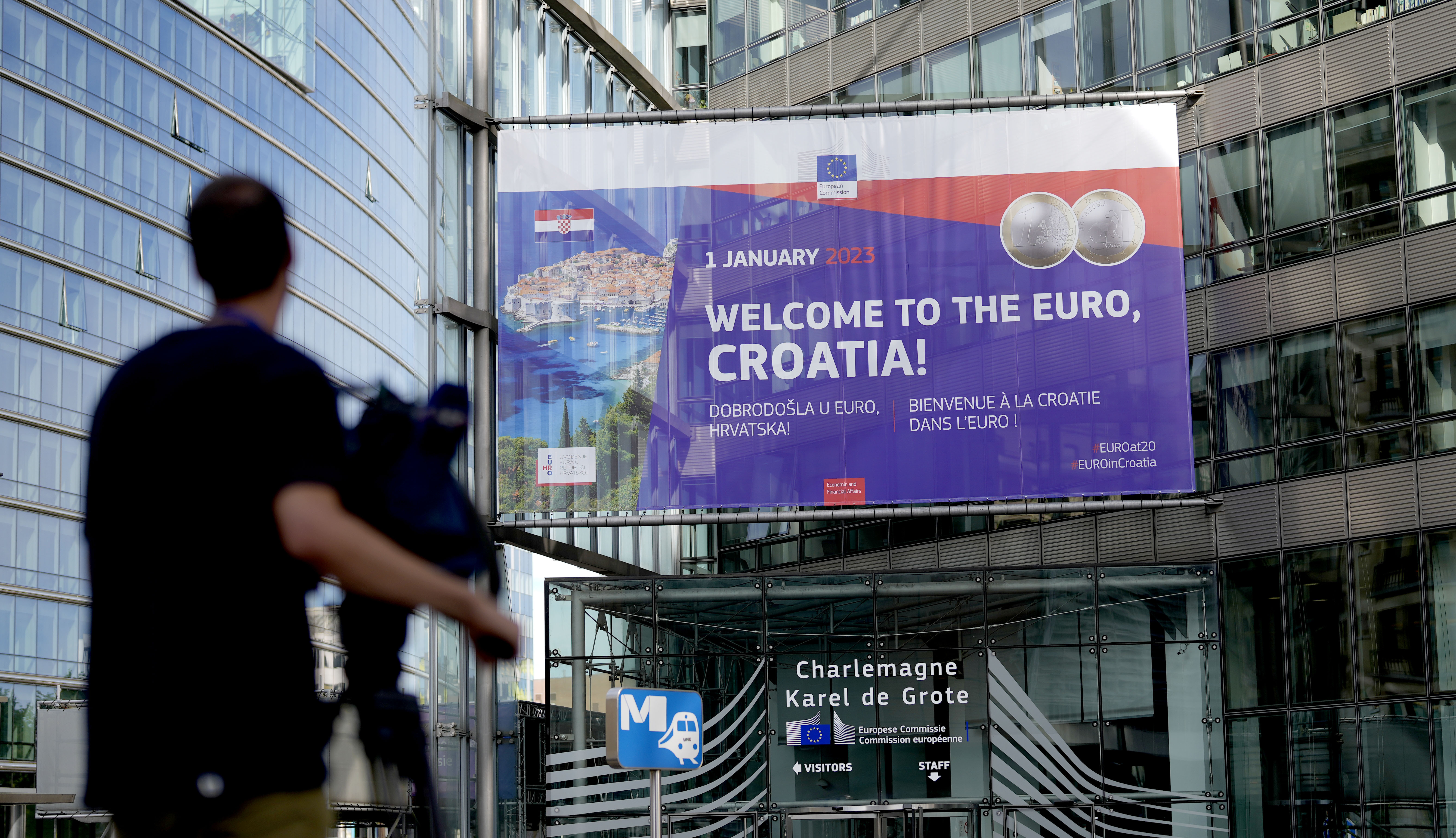 A video journalist films a banner welcoming Croatia to the eurozone in front of the EU headquarters in Brussels
