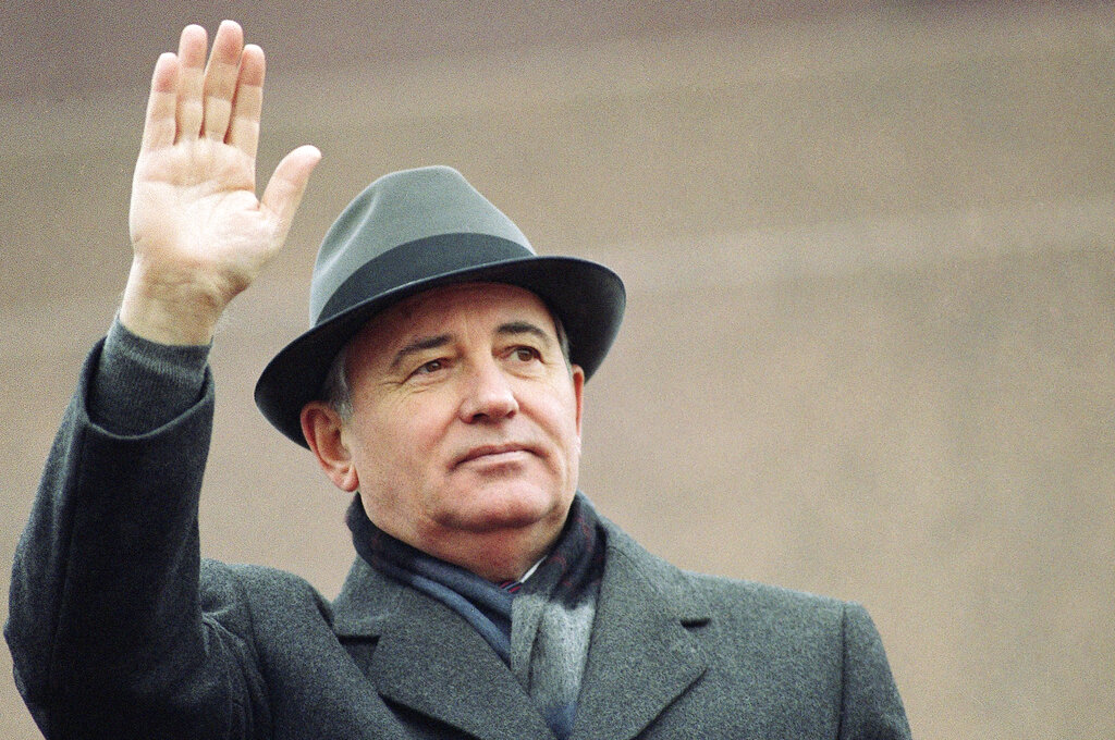 Mikhail Gorbachev in grey hat and coat waves to a crowd in 1989