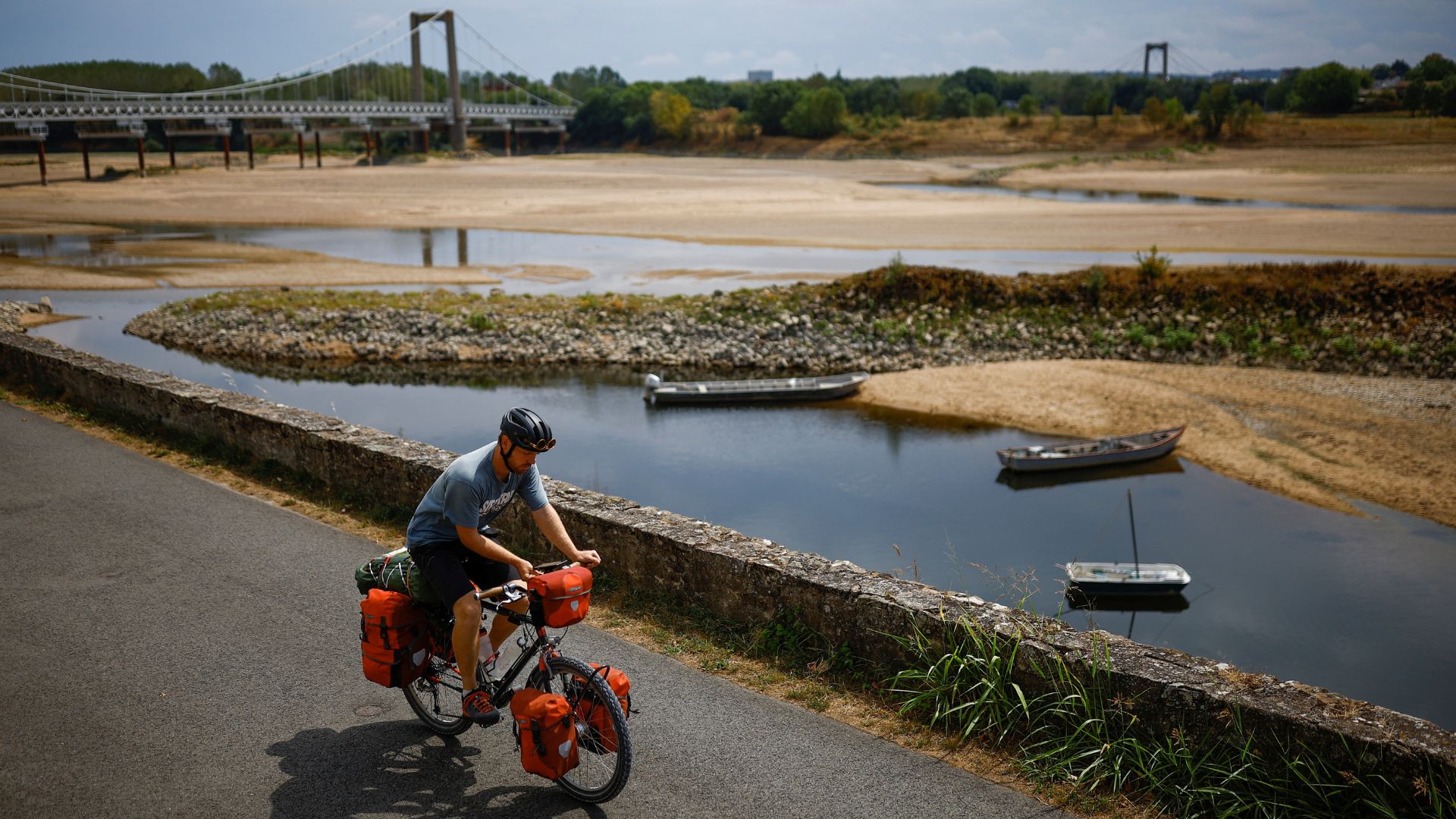 A cyclist rides near a branch of the Loire River as historical drought hits France