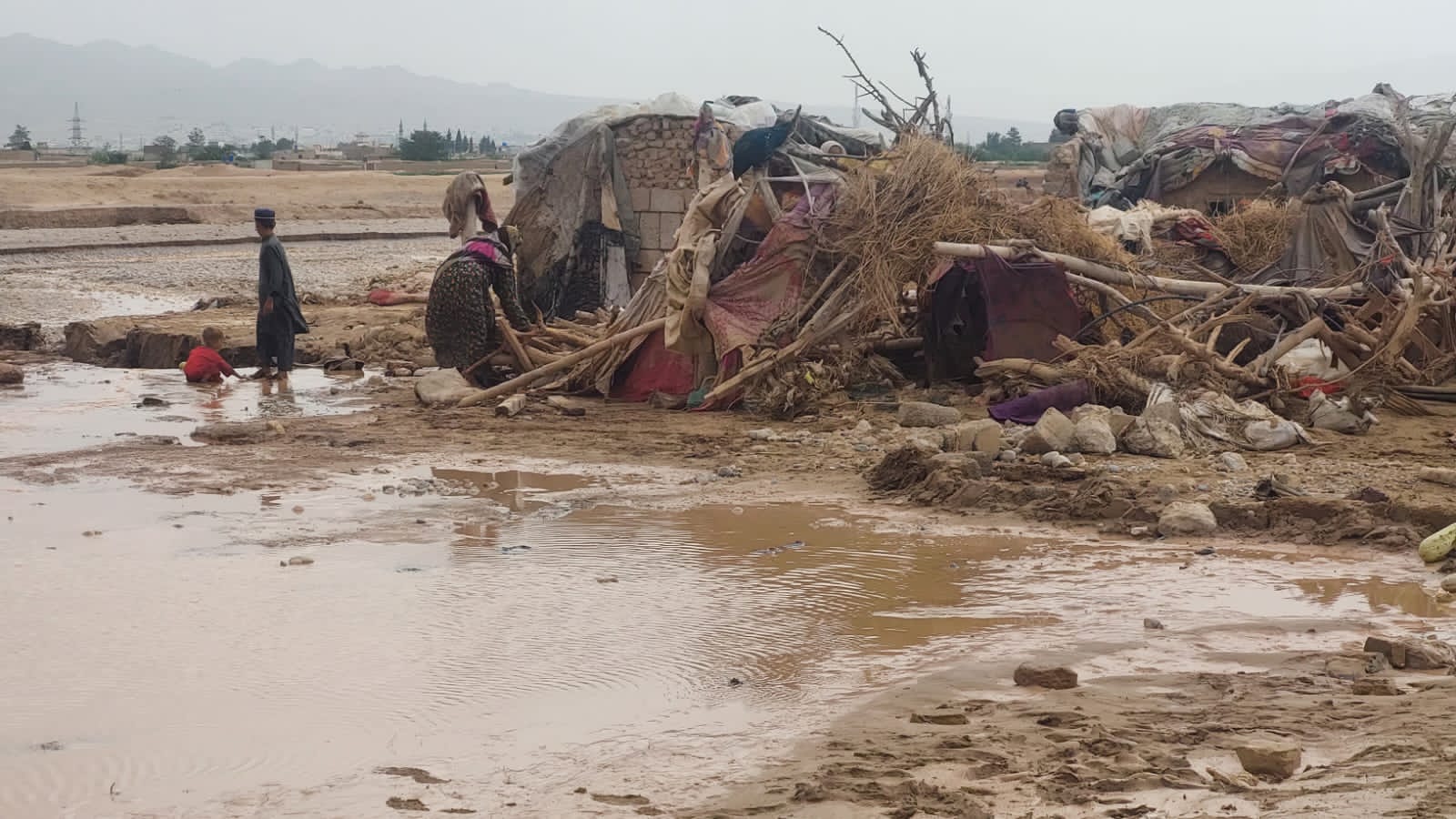 A woman and her children outside their damaged house in Killi Almas on the outskirts of Quetta