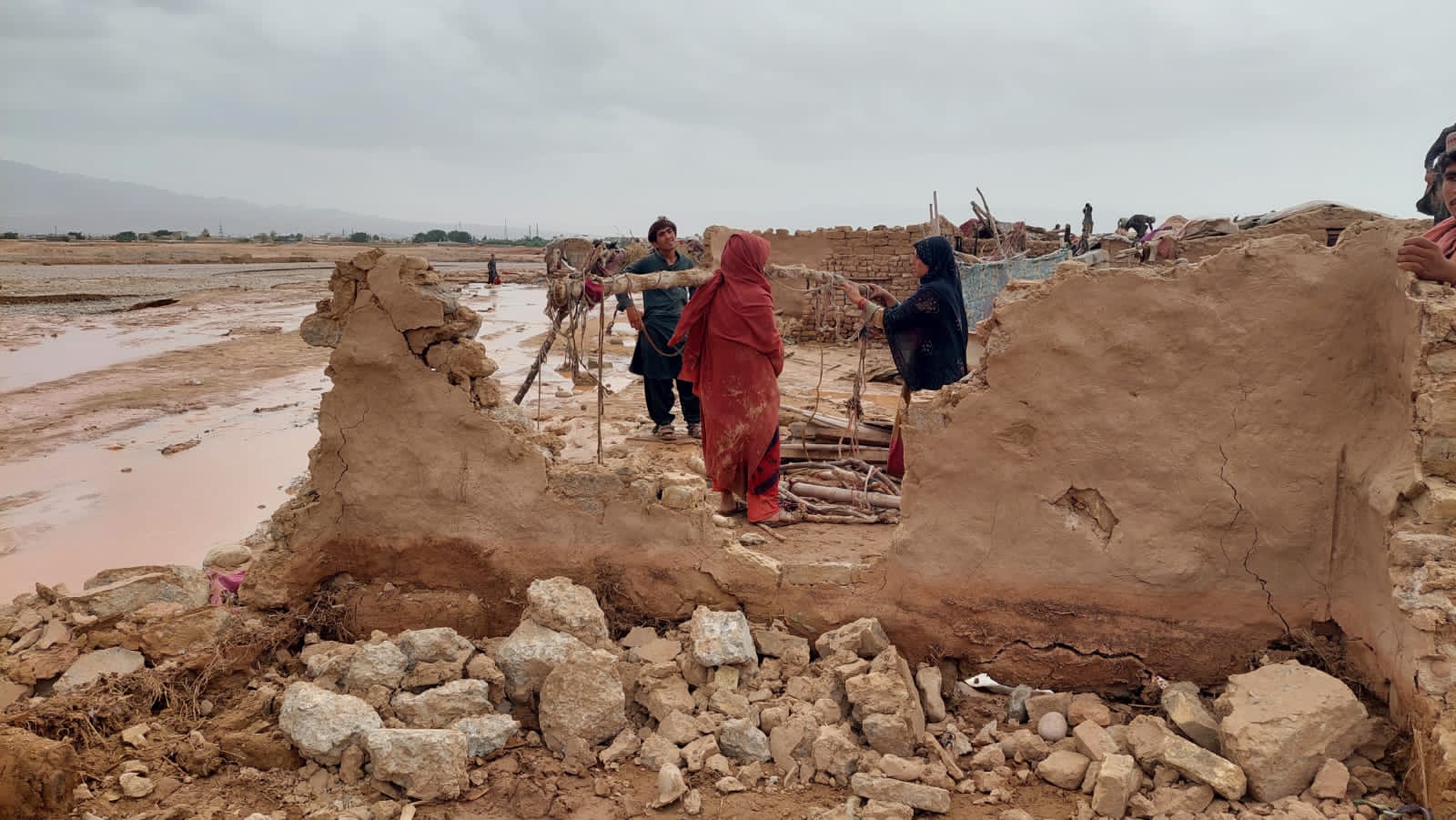 Women stand outside their collapsed houses in Killi Almas on the outskirts of Quetta